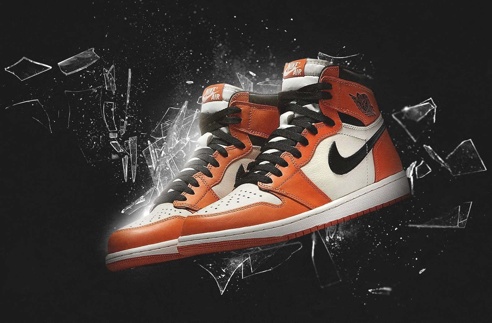 桌布 壁紙 — 一雙橘色和白色的 Air Jordan 1 運動鞋在黑色背景上衝破碎玻璃。