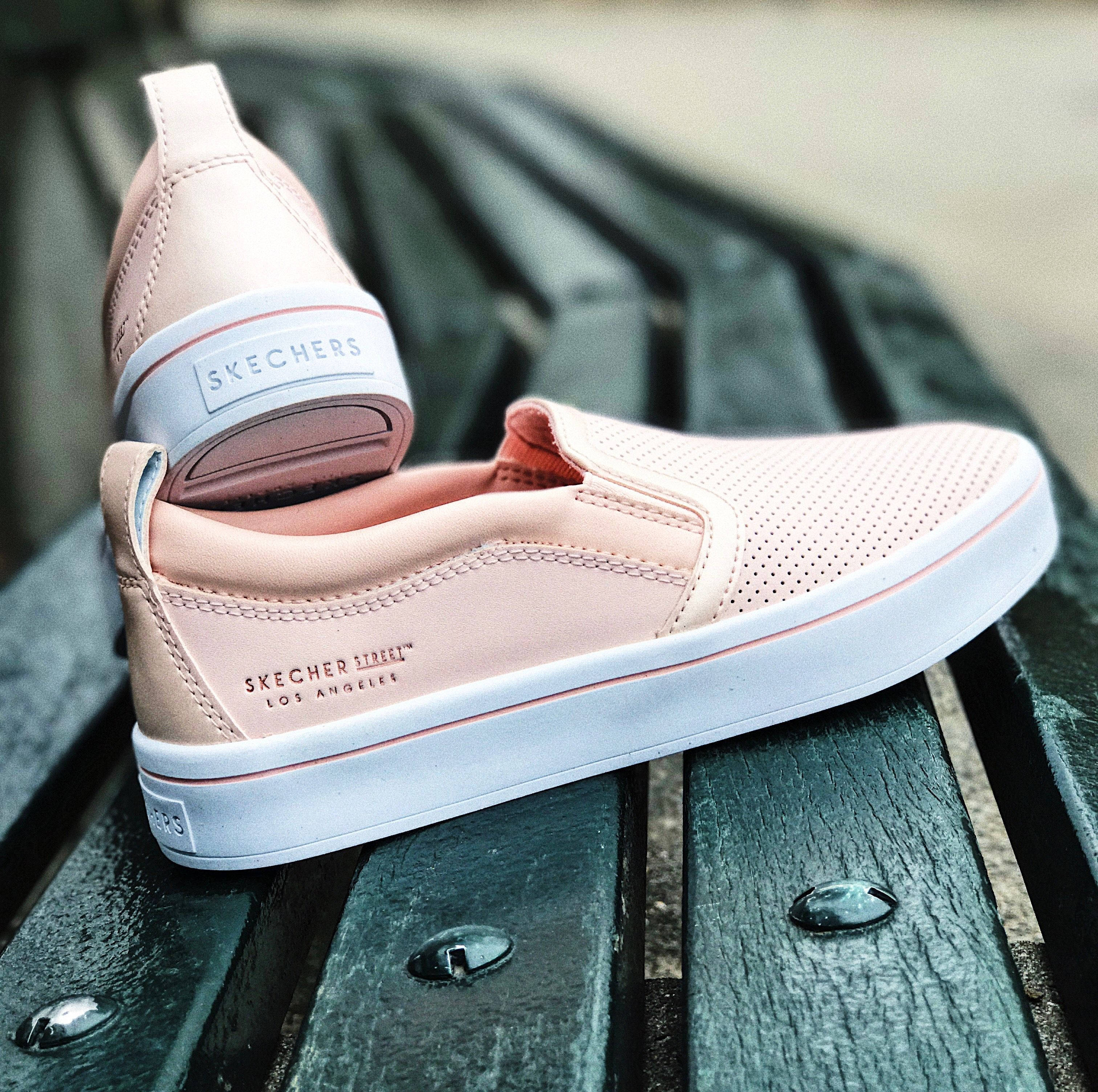 Skechers 桌布 壁紙 — 一雙淡粉紅色Skechers slip-on運動鞋隨意地放在一張歷經風霜的綠色公園長椅上。