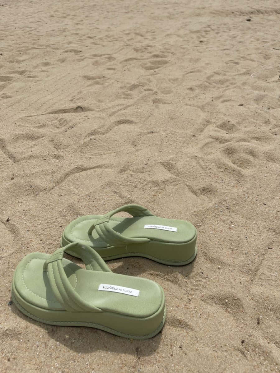 Beach Sandals 桌布 壁紙 — 一雙淺綠色厚底涼鞋在明亮的日光下放置在質感沙地上。