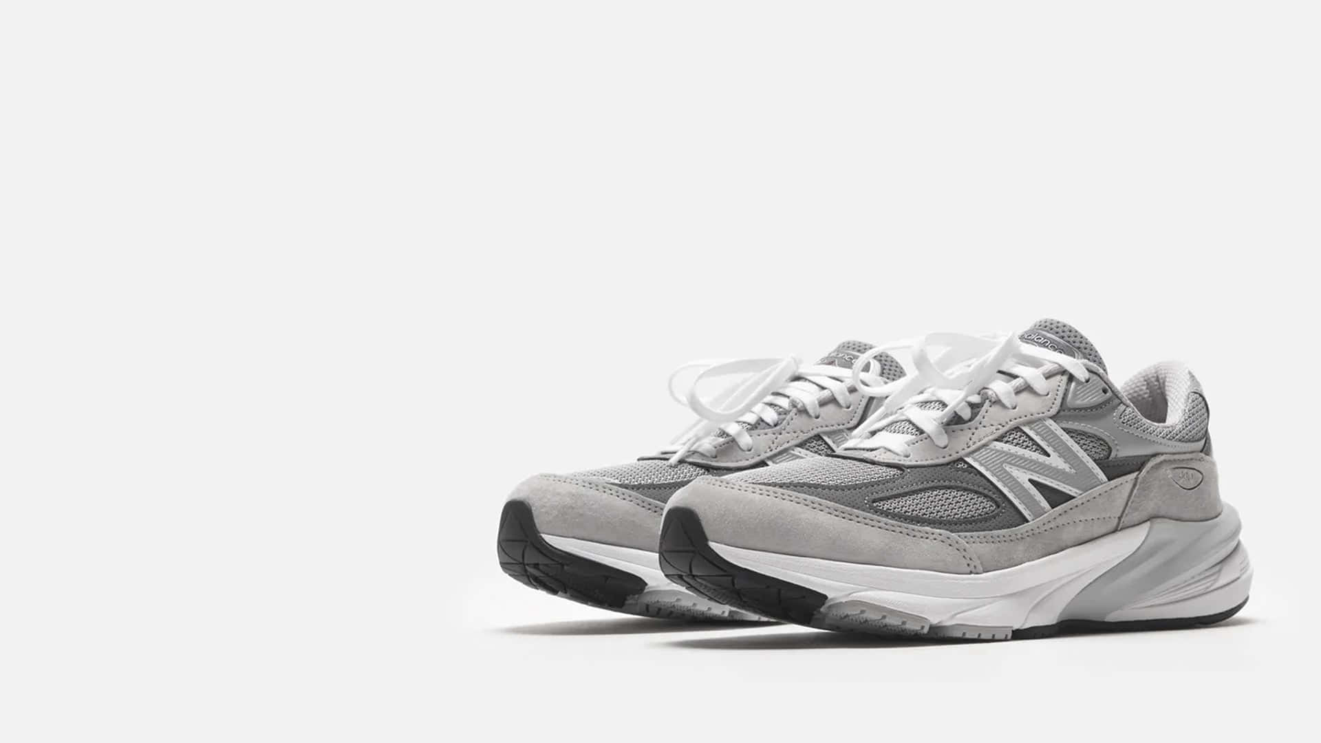 New Balance 桌布 壁紙 — 一雙灰色 New Balance 運動鞋，搭配白色鞋帶和厚鞋底，在純白色背景前拍攝。
