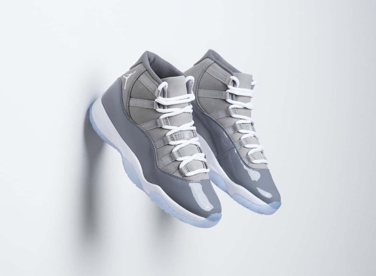 Sneakers 桌布 壁紙 — 一雙灰色高筒運動鞋，帶有白色鞋帶和淺藍色鞋底，掛在純白色牆上。