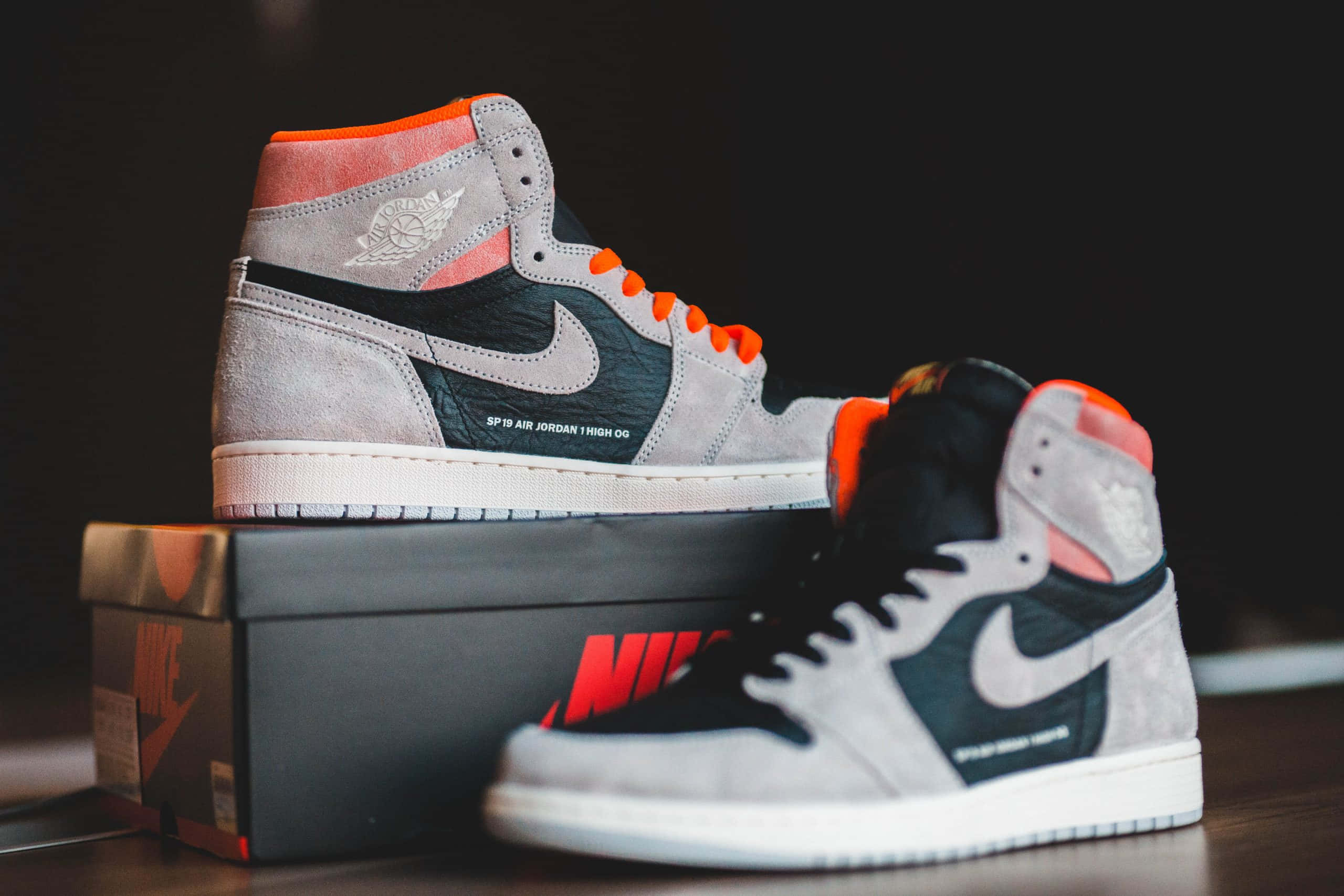 Dope Jordan 桌布 壁紙 — 一雙灰黑橙色的高筒 Air Jordan 1 運動鞋放在 Nike 鞋盒上，營造出戲劇性的淺景深效果。