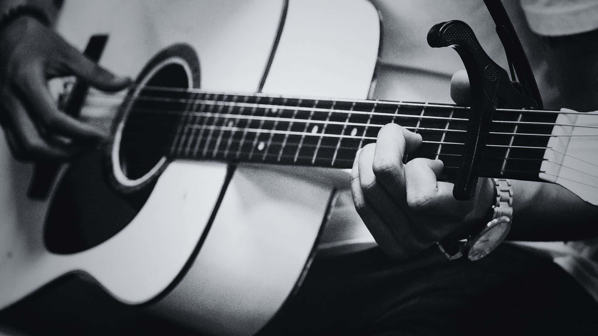 Black And White Guitar 桌布 壁紙 — 一雙熟練彈奏帶有變調夾的木吉他的手部黑白特寫。