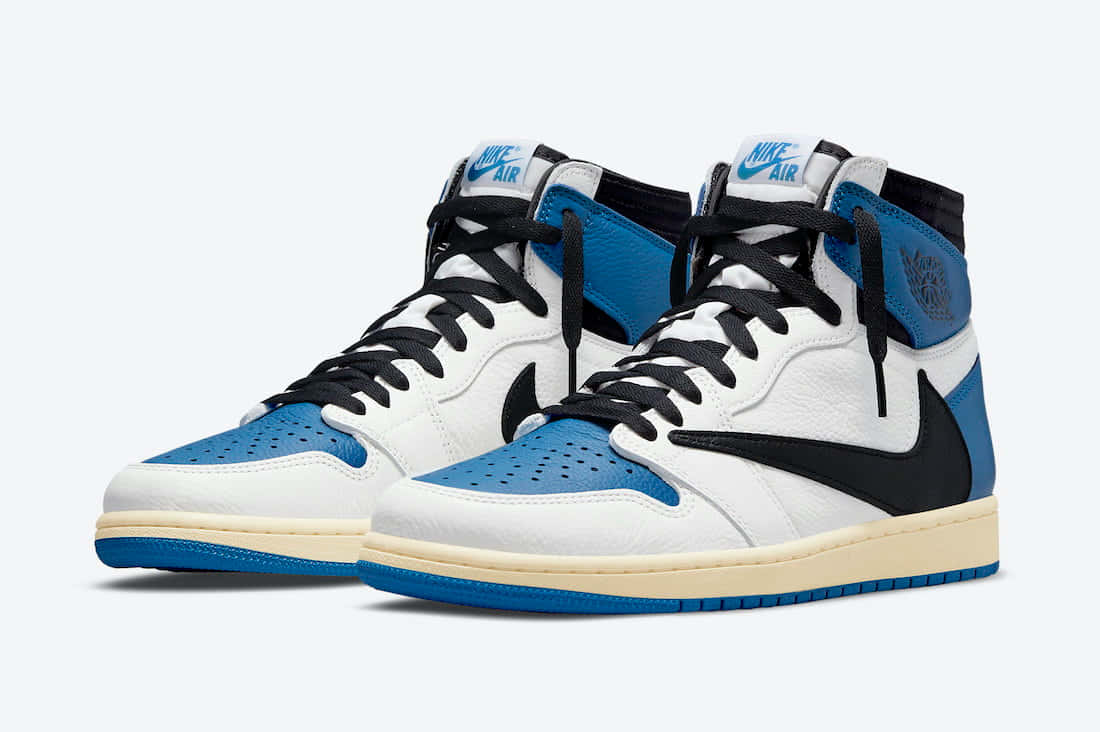 Travis Scott Jordan 1 桌布 壁紙 — 一雙白色、藍色和黑色的高筒運動鞋，帶有Nike Air品牌標誌和穿孔鞋頭。