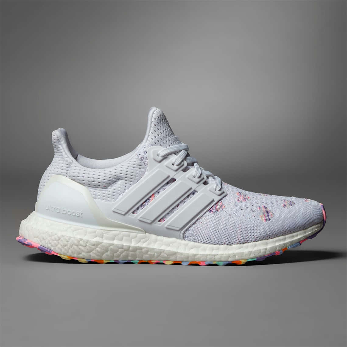 愛迪達 桌布 壁紙 — 一雙白色Adidas Ultra Boost運動鞋，鞋底和鞋面帶有彩色斑點裝飾，背景為中性灰色。