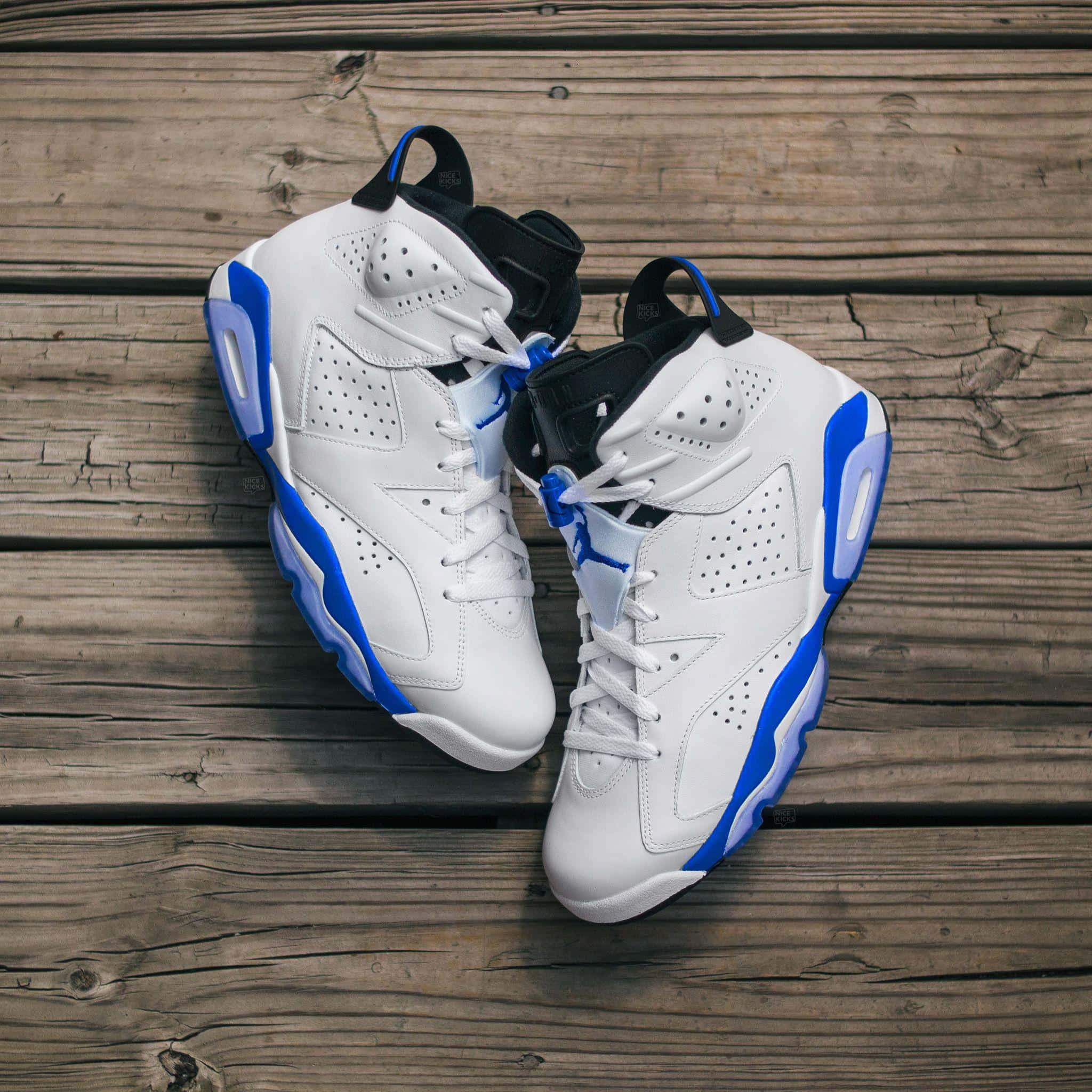 Jordan球鞋 桌布 壁紙 — 一雙白色和藍色的Jordan 6運動鞋放在風化的木板上，從上方俯視。