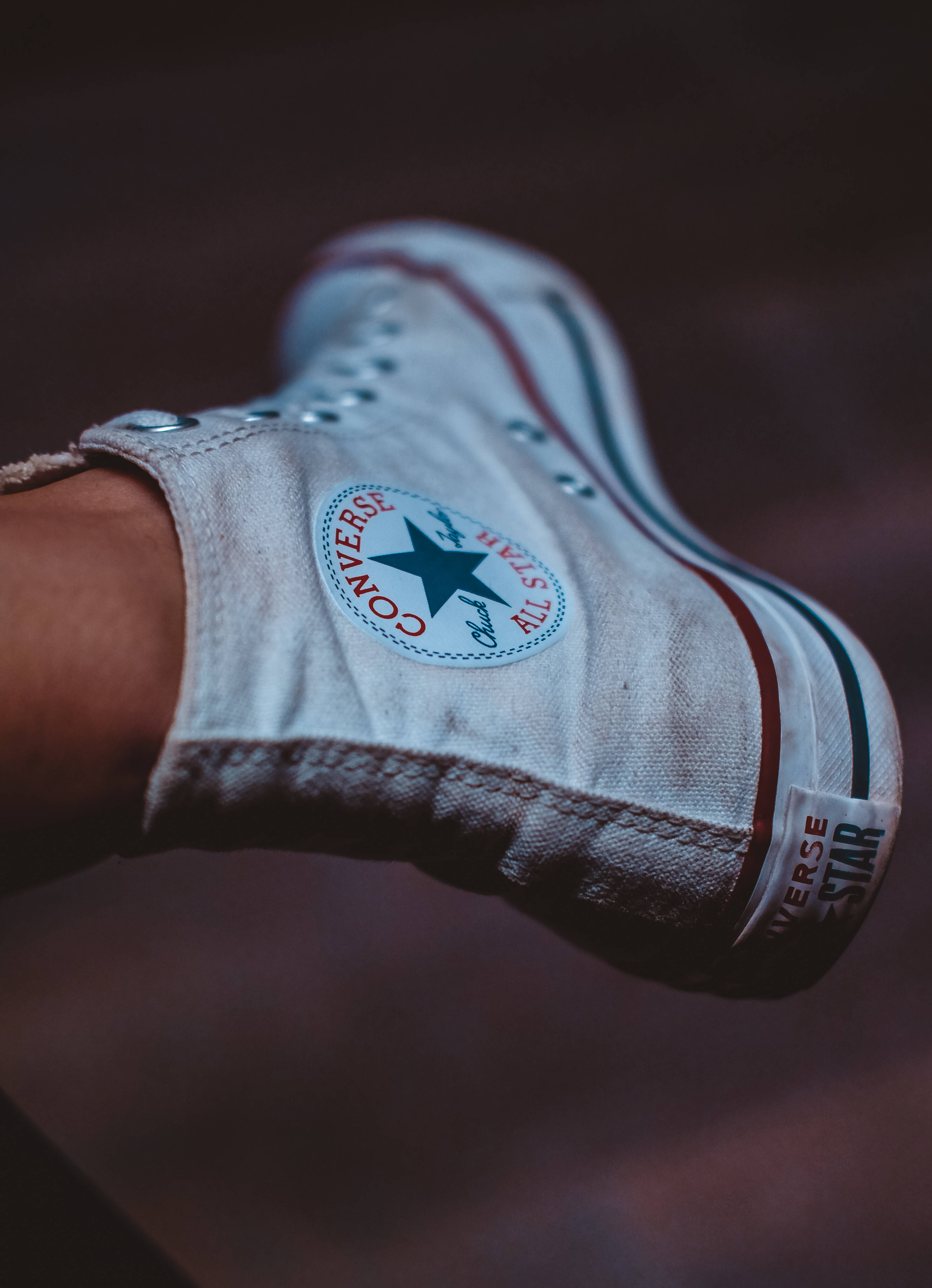 Converse 桌布 壁紙 — 一雙磨損的白色Converse運動鞋特寫，帶有紅色和黑色條紋，背景為深色模糊。