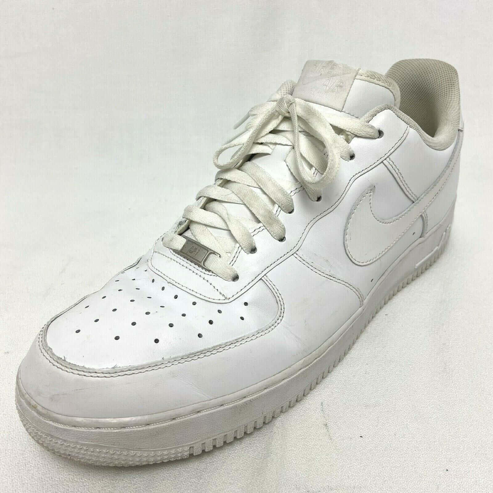 Nike Air Force 桌布 壁紙 — 一雙磨損的白色Nike Air Force 1運動鞋，皮革有刮痕，鞋帶骯髒，放在純白色背景上。