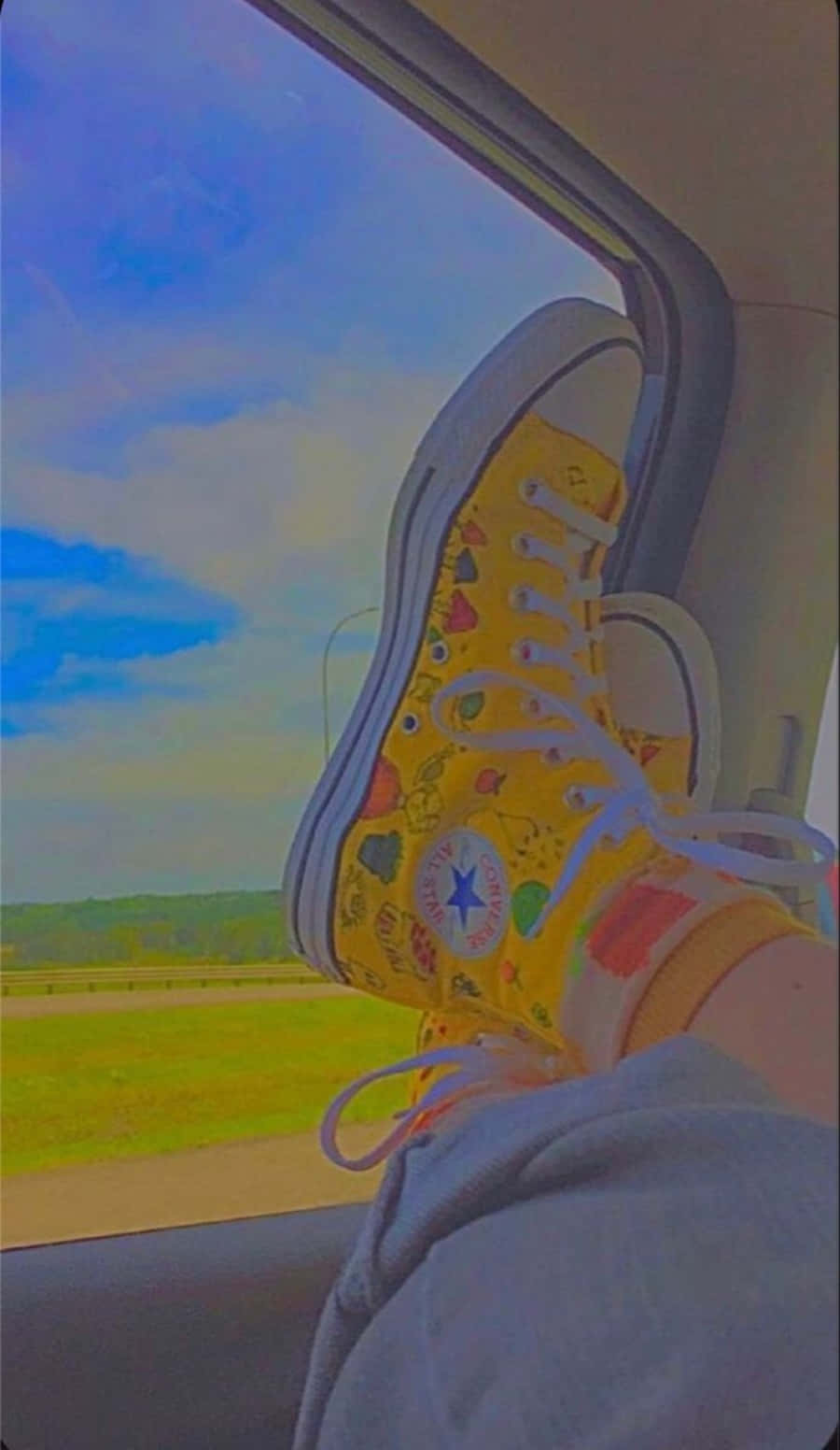 一雙穿著黃色Converse鞋的腳坐在車內 壁紙