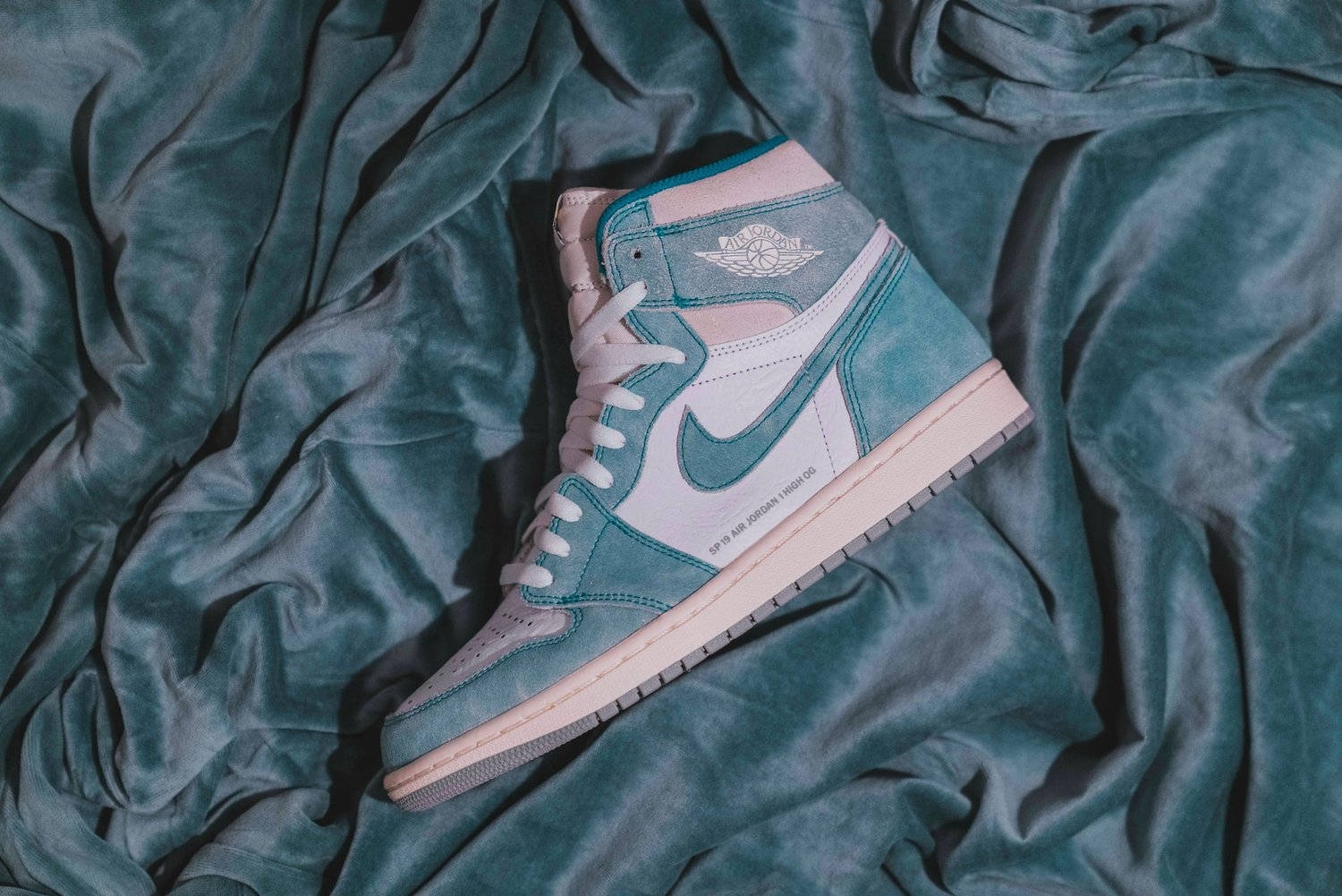 Nike Logo 桌布 壁紙 — 一雙粉藍色和粉紅色的高筒運動鞋放在皺巴巴的粉藍色天鵝絨布料上，光線柔和。