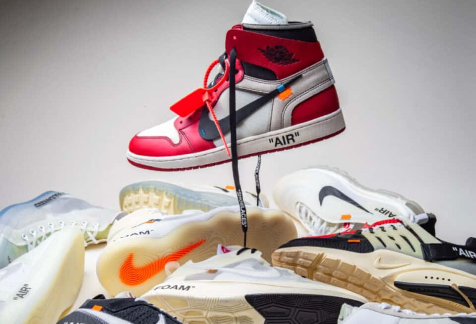 Sneakerhead 桌布 壁紙 — 一雙紅、白、黑色高筒運動鞋漂浮在其他設計師運動鞋堆之上，背景為純灰色。
