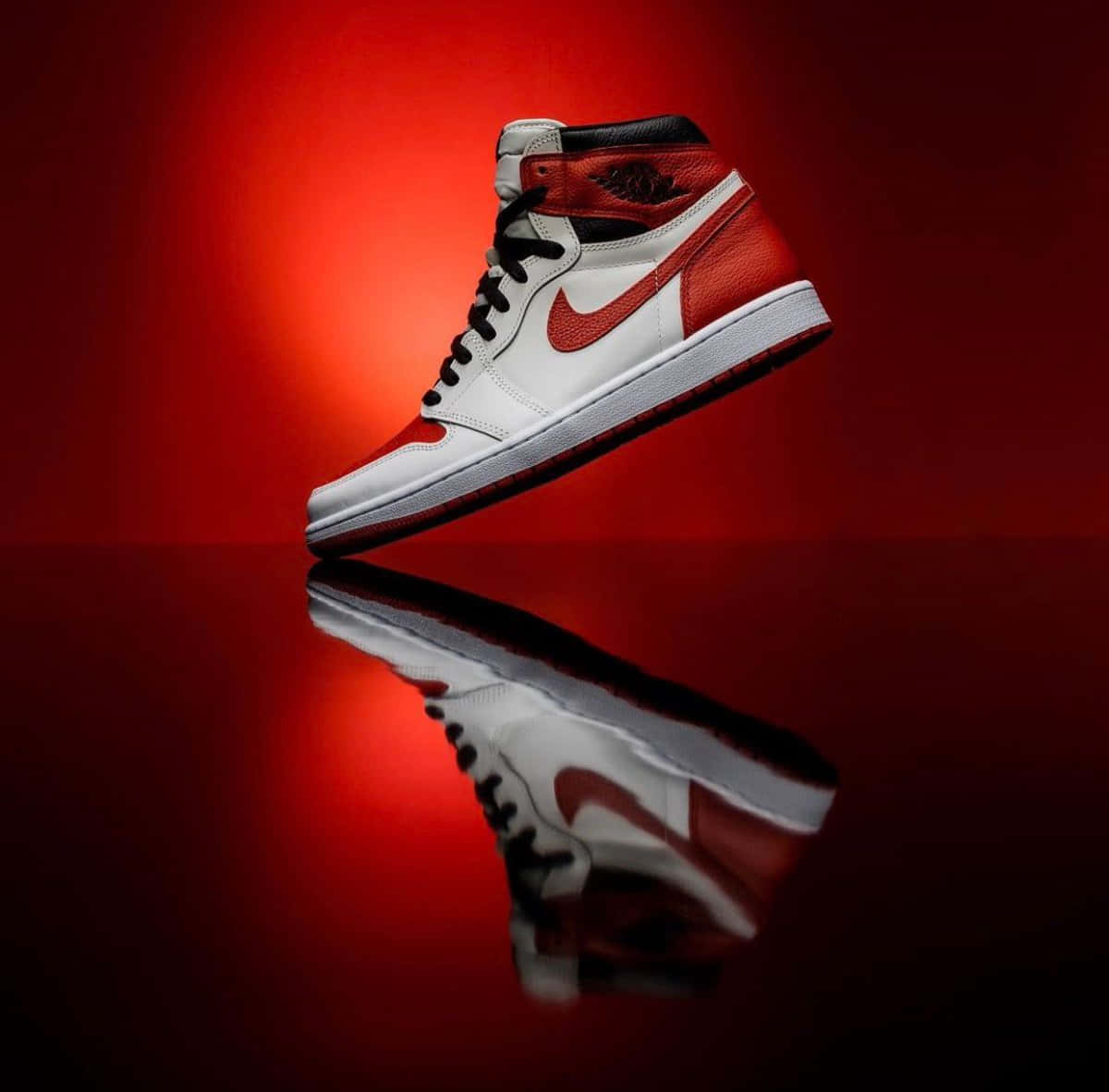 Air Jordan 1 桌布 壁紙 — 一雙紅白Jordan 1運動鞋漂浮在反光表面上，背景為漸層紅色。
