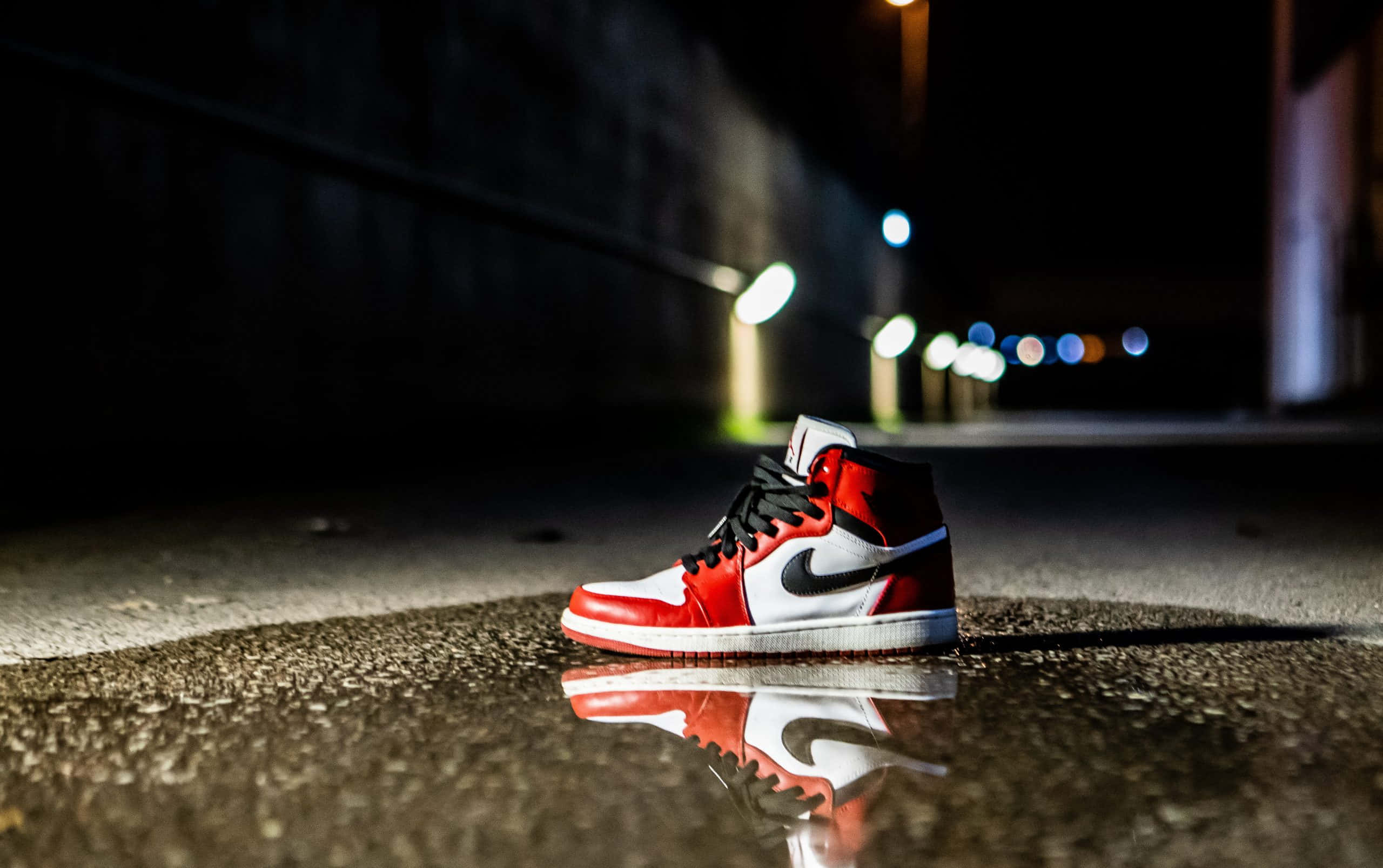 Dope Jordan 桌布 壁紙 — 一雙紅白高筒運動鞋放在水坑中，水坑反射著夜間黑暗城市隧道下的街燈。