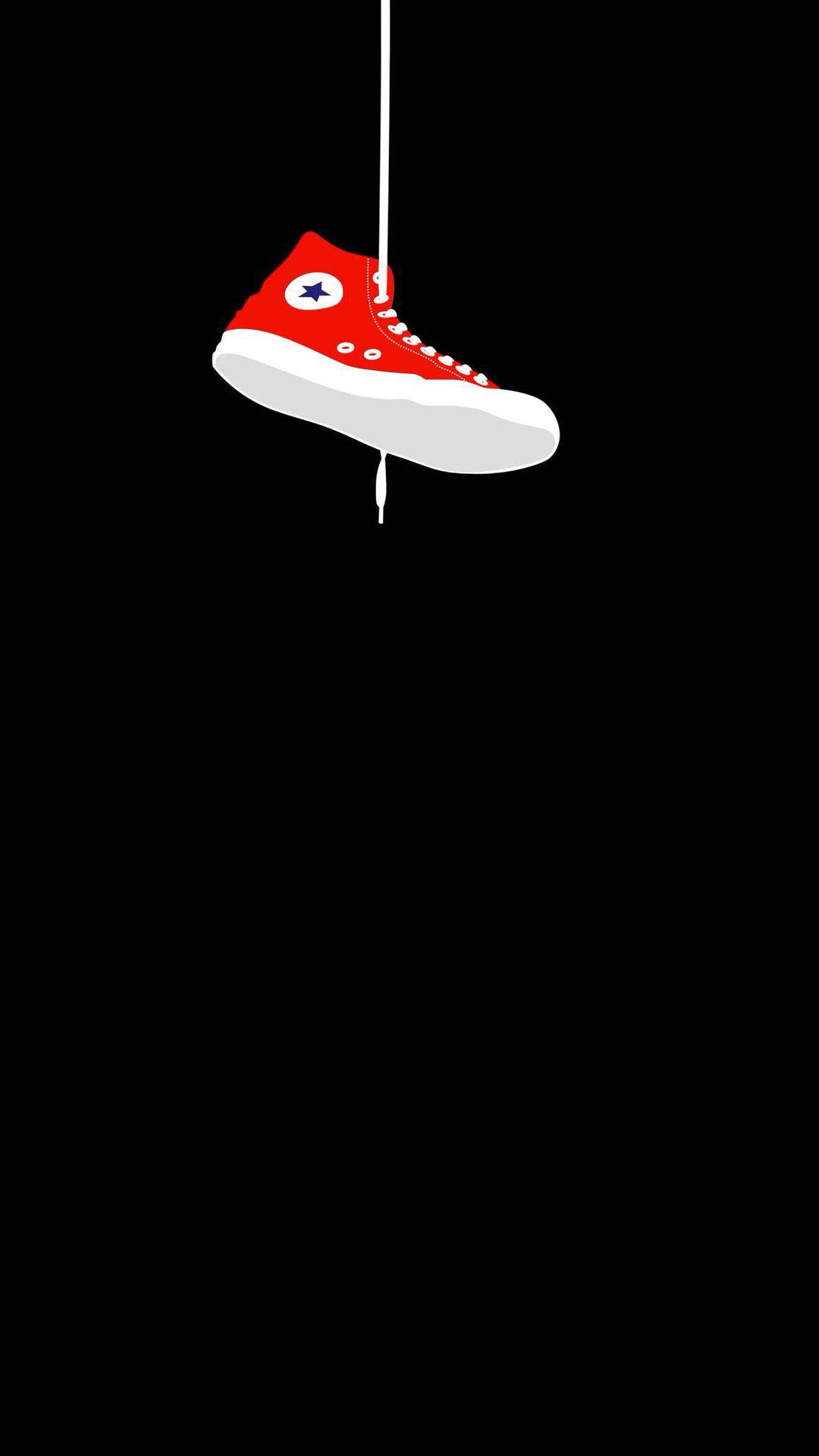 Converse 桌布 壁紙 — 一雙紅色高筒運動鞋，白色鞋底和星星標誌，用白色繩子懸掛在純黑色背景上。