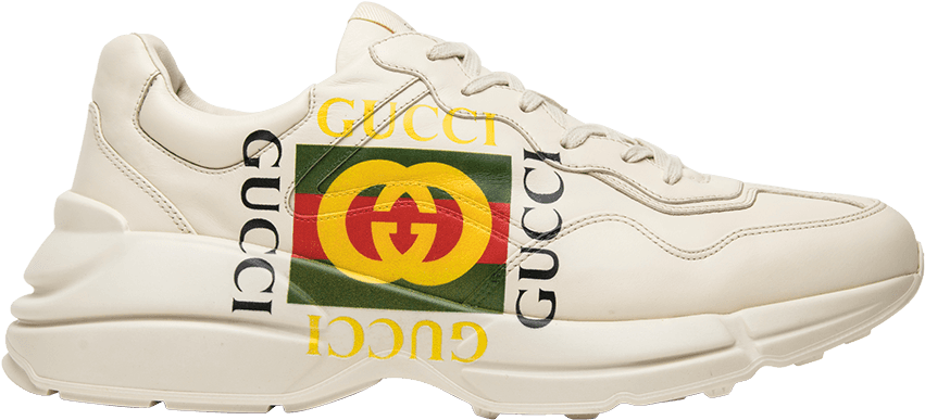 Gucci 桌布 壁紙 — 一雙純白色的 Gucci 運動鞋，帶有醒目的黃色、黑色和紅色品牌標誌，襯托在純黑色背景上。