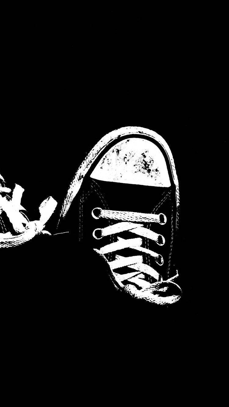 Converse 桌布 壁紙 — 一雙純白色高筒運動鞋，帶有鞋帶和磨損的鞋頭，在純黑色背景上格外突出。