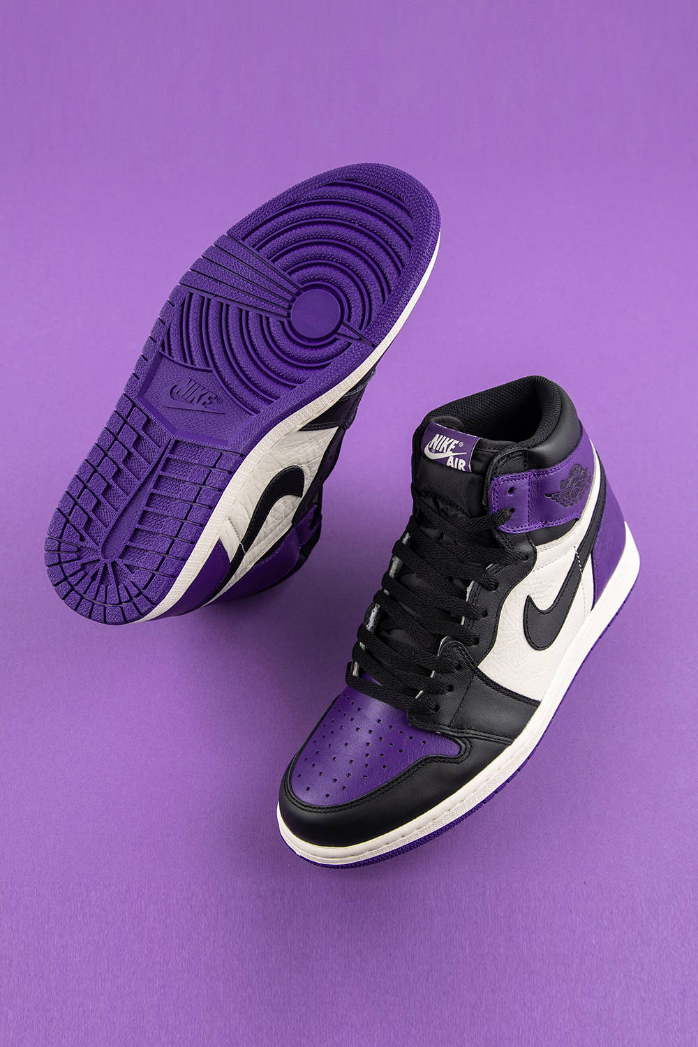 Purple Jordan 桌布 壁紙 — 一雙紫、黑、白色Nike Air Jordan 1運動鞋，展示在純紫色背景上。