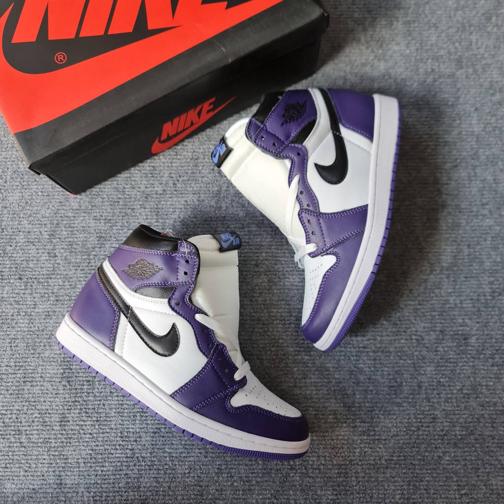 Nike Logo 桌布 壁紙 — 一雙紫色、白色和黑色的高筒運動鞋放在灰色紋理表面上，旁邊有一個紅色和黑色的Nike盒子。