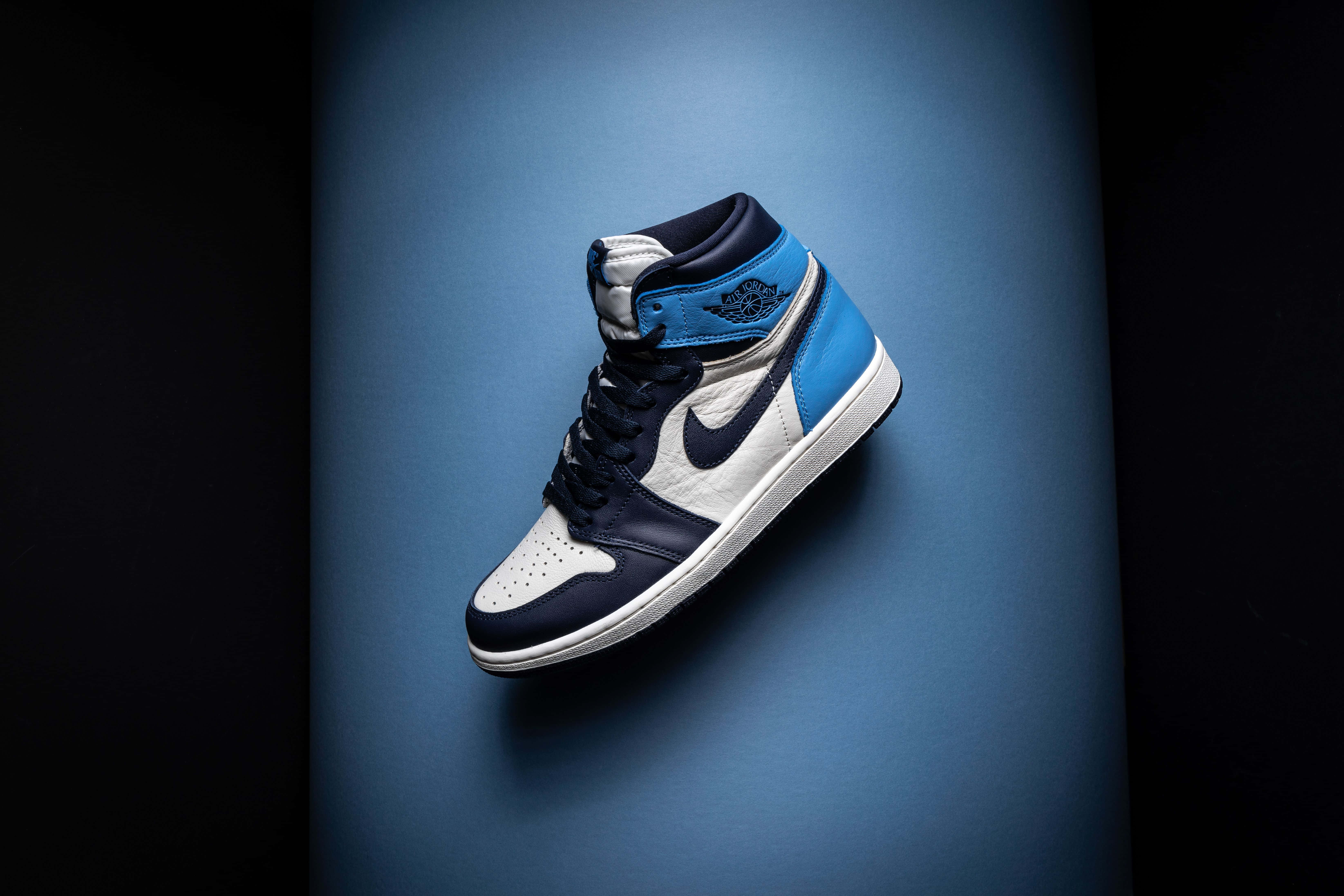 Air Jordan 桌布 壁紙 — 一雙藍白高筒運動鞋在漸變藍色背景上漂浮，帶有戲劇性的工作室燈光。