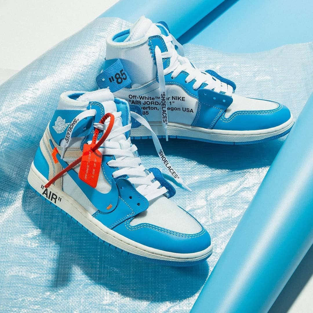 off white 桌布 壁紙 — 一雙藍白高筒運動鞋帶有紅色標籤，在明亮的陽光下放置於皺巴巴的藍色塑膠表面上。