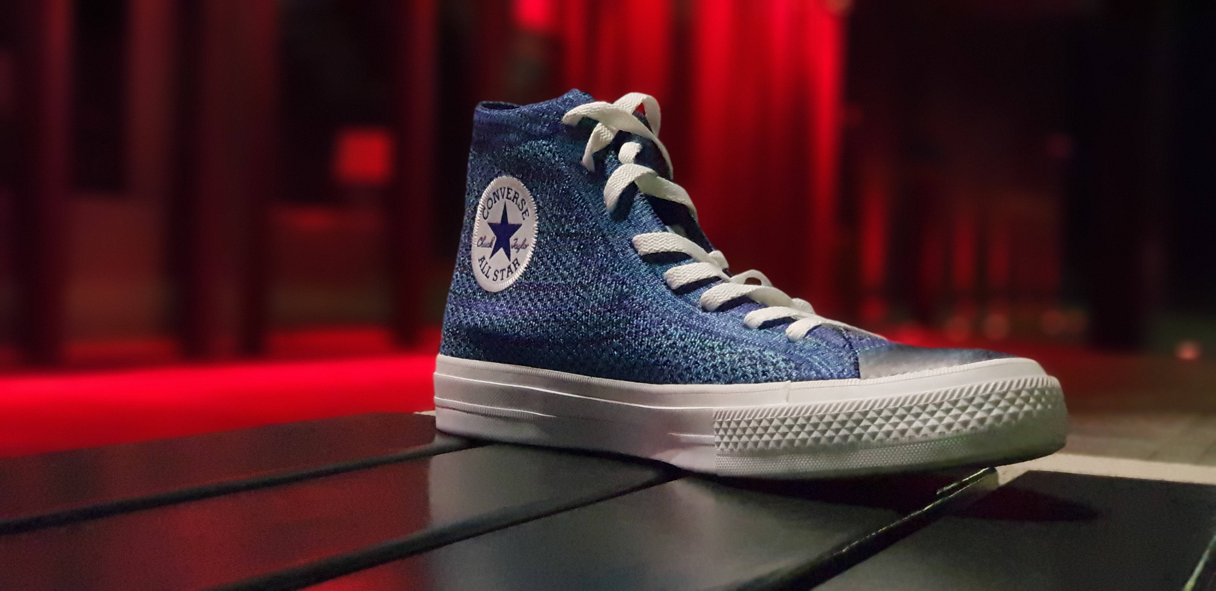 Sneaker 桌布 壁紙 — 一雙藍色針織高筒Converse運動鞋，白色鞋帶，放在深色木質表面上，在溫暖的紅色環境燈光下。