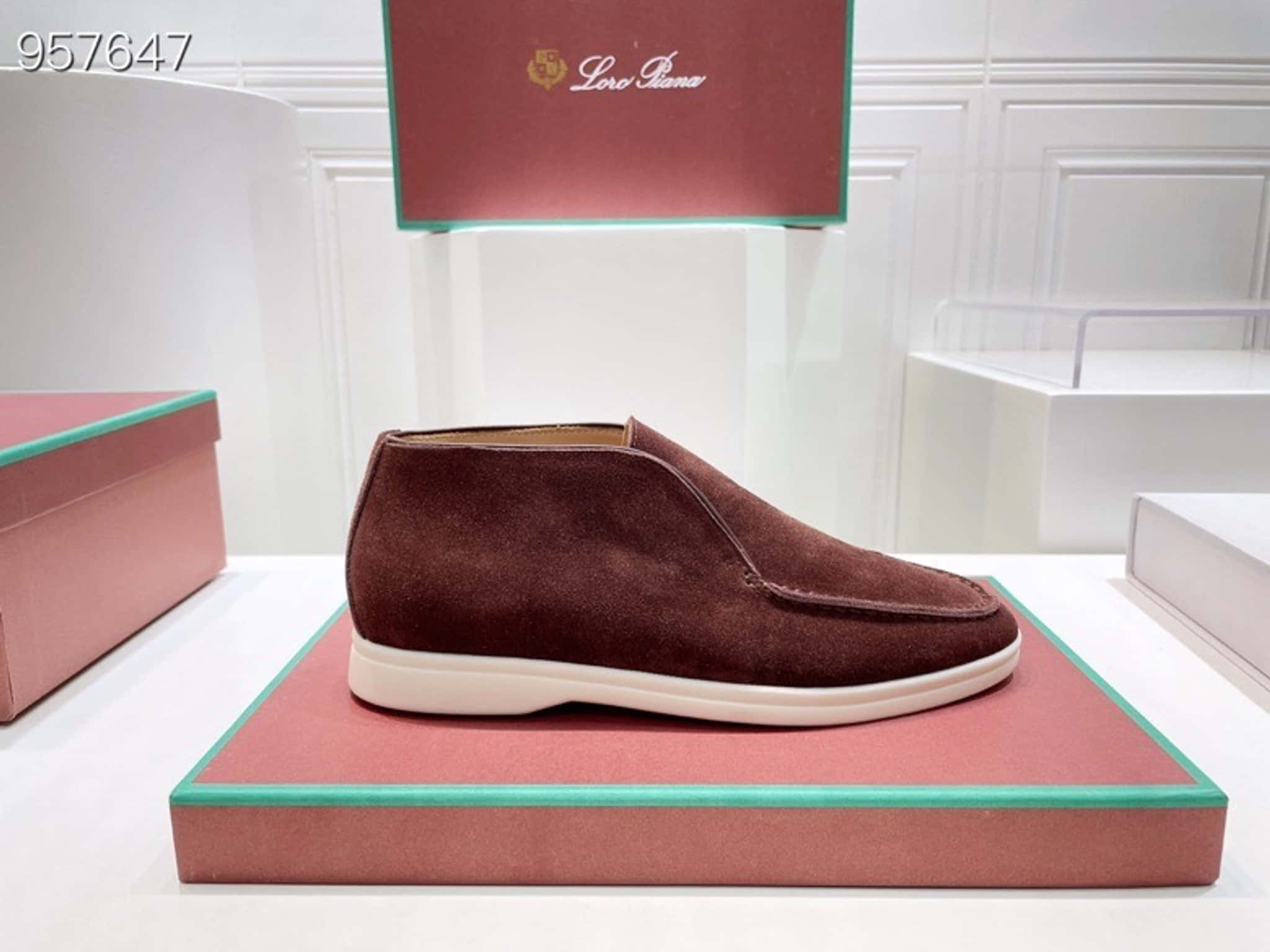 Shoe 桌布 壁紙 — 一雙酒紅色麂皮Lorena Piana查卡鞋，展示在帶有青綠色飾邊的粉紅色平台上，置於簡約白色零售環境中。