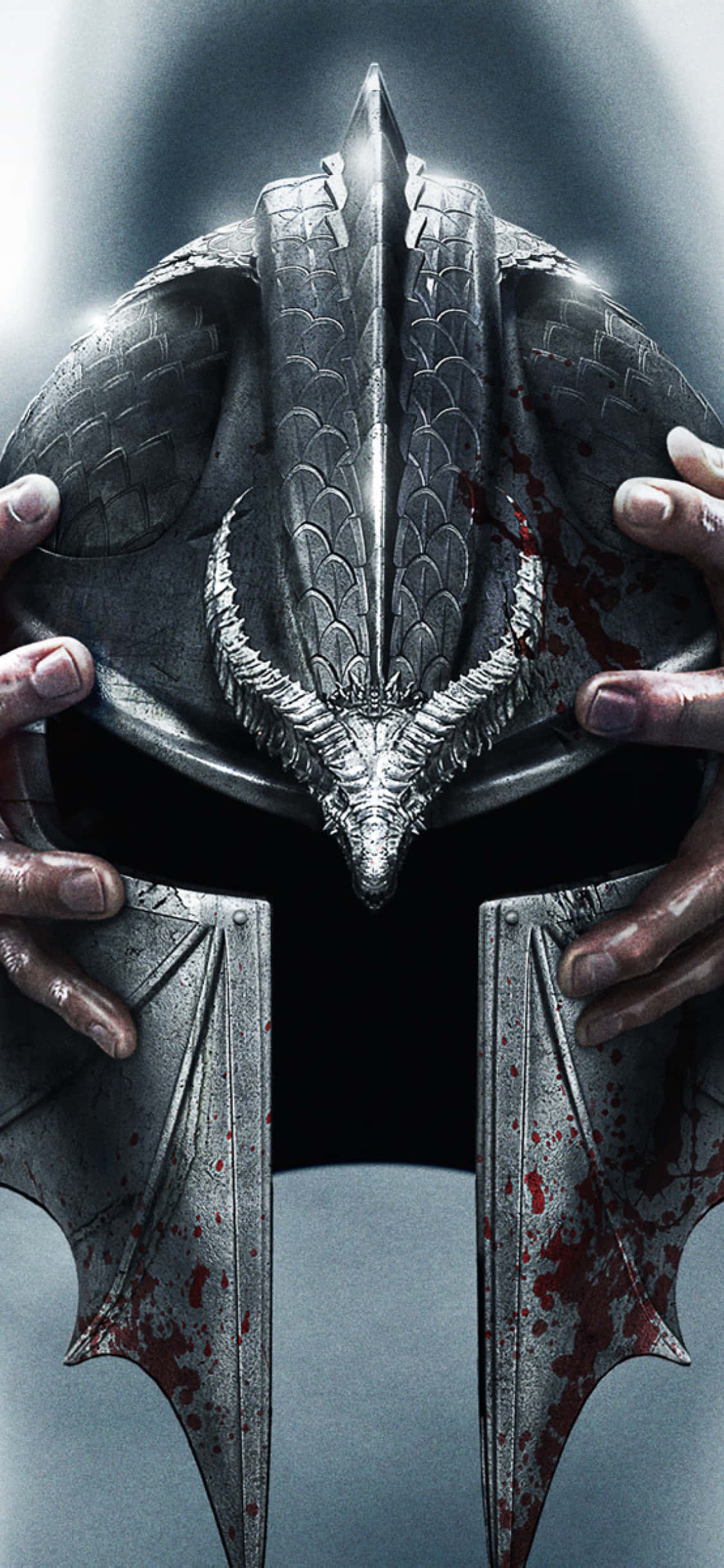 iPhone Xs Dragon Age Inquisition 桌布 壁紙 — 一雙骯髒的手在黑暗背景下握著一個沾滿血跡的金屬龍頭盔，上面有精細的鱗片和角。
