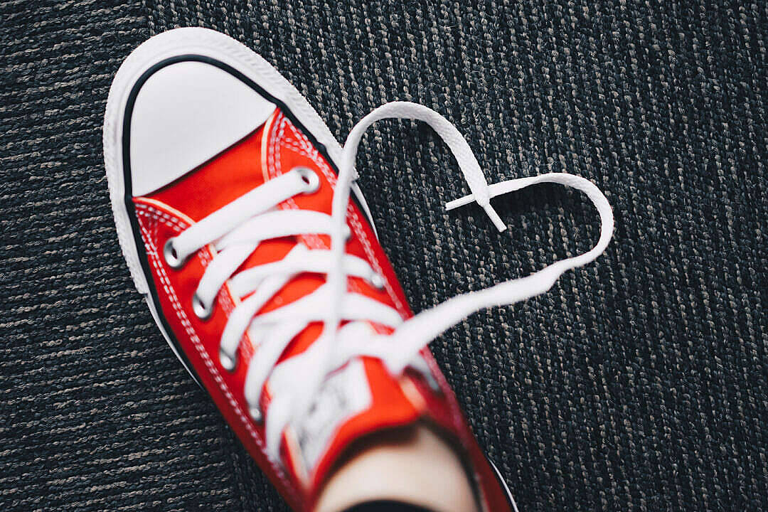 Shoe 桌布 壁紙 — 一雙鮮紅色運動鞋，白色鞋帶繫成心形，放在深色紋理地毯上。