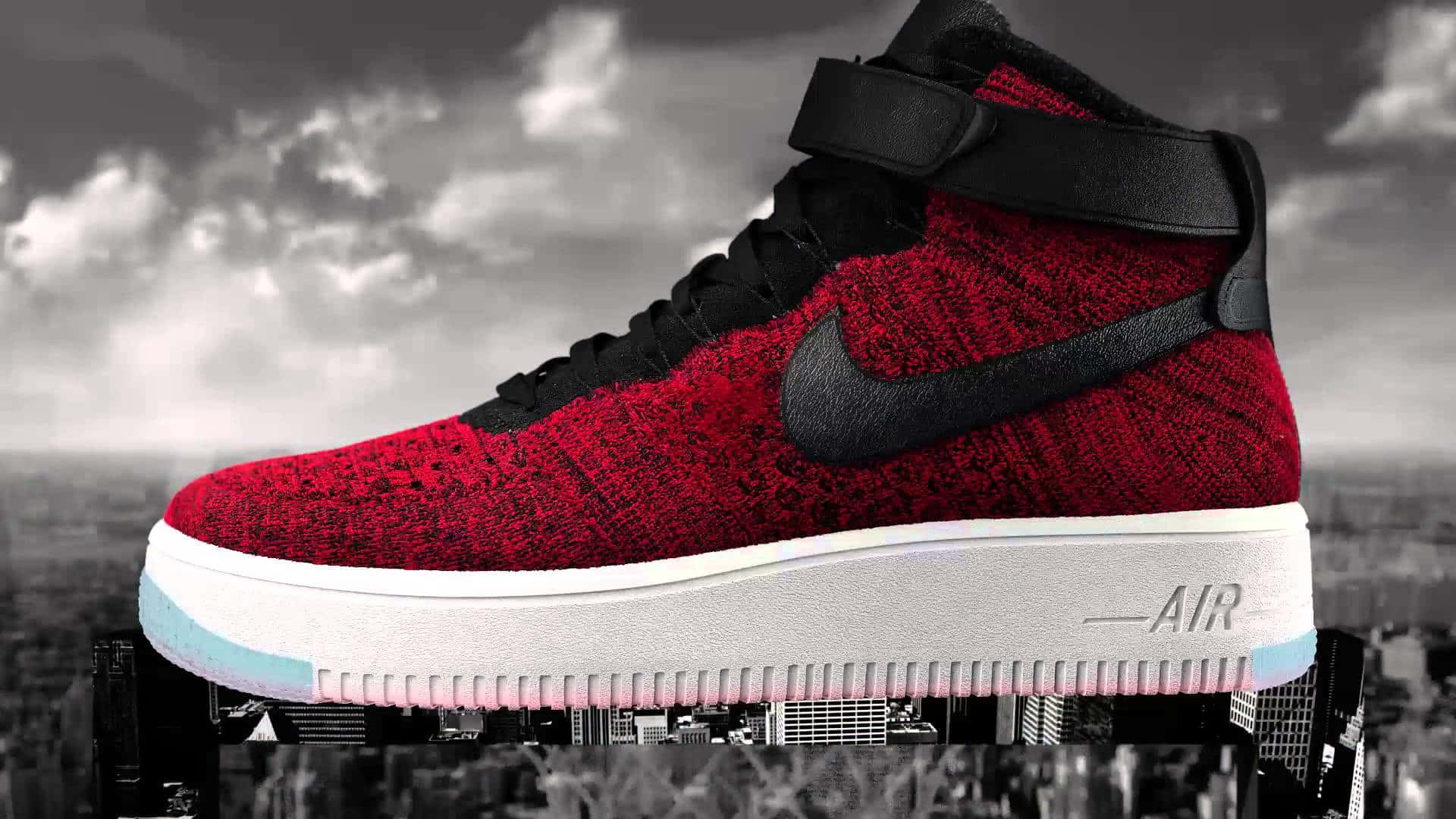 Nike 桌布 壁紙 — 一雙鮮紅色高筒運動鞋帶有黑色勾勾，漂浮在陰天下的單色城市景觀之上。