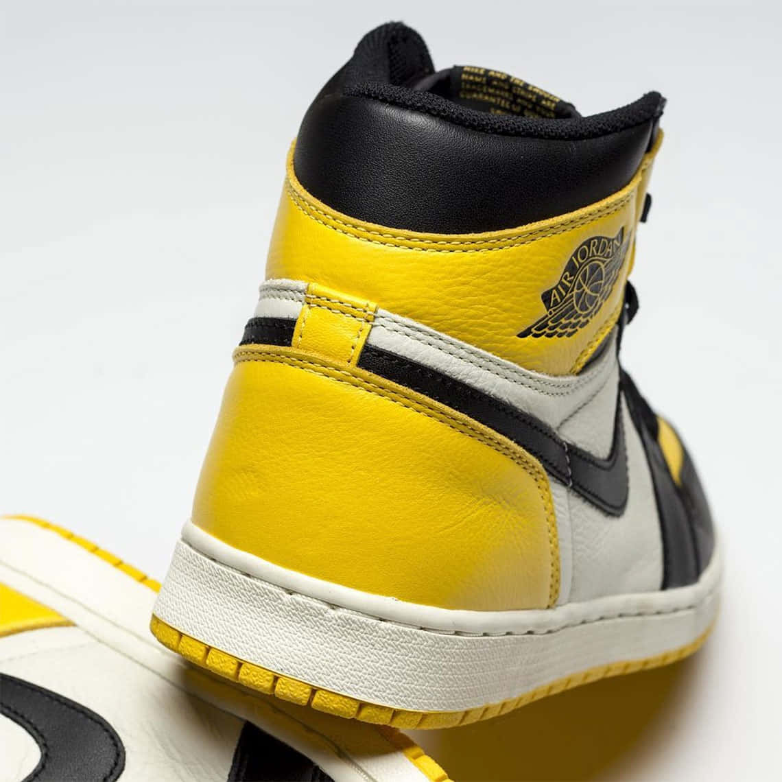 Yellow Jordan 桌布 壁紙 — 一雙黃、黑、白色高筒運動鞋的特寫，展示Air Jordan標誌和紋理皮革細節。