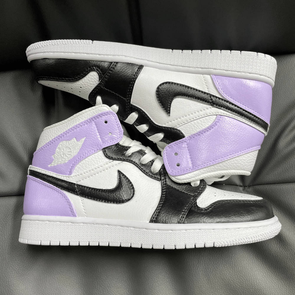 品牌 桌布 壁紙 — 一雙黑、白和薰衣草色的Jordan 1運動鞋隨意地放在深灰色皮革沙發上。