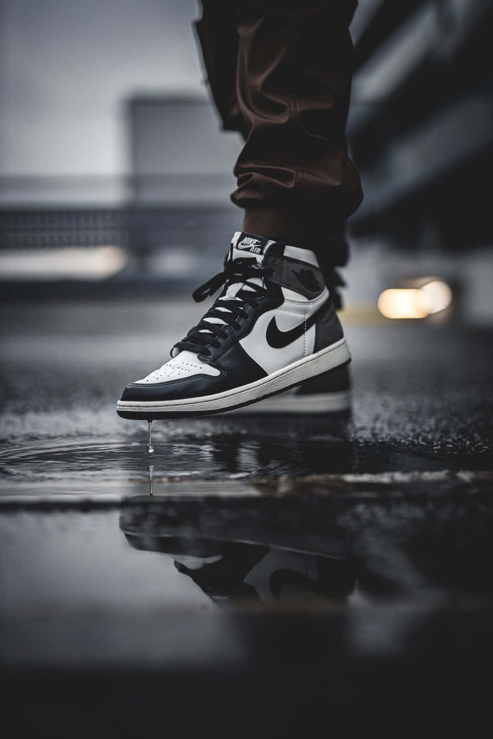 黑白運動鞋在夜晚濕漉漉的城市路面上滴水。 — Air Jordan 1 壁紙