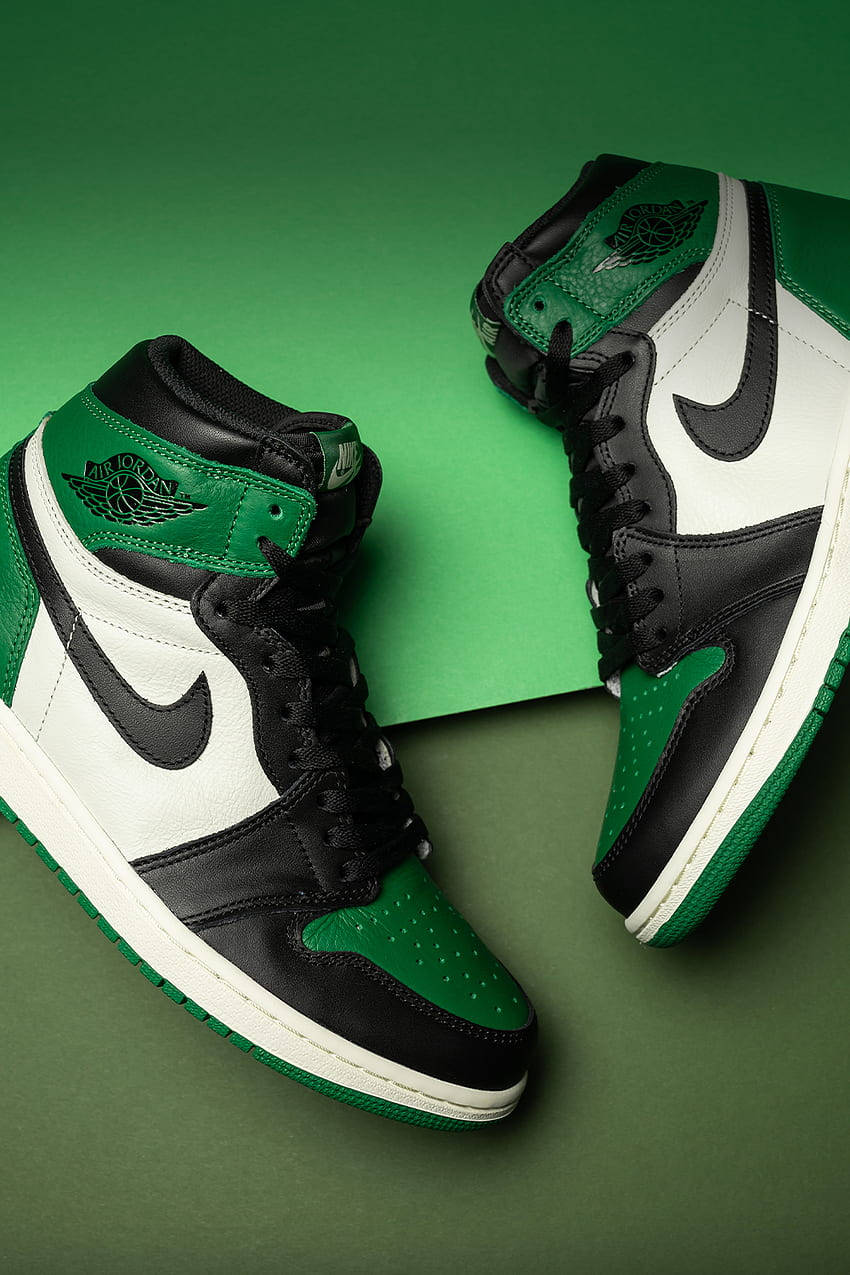 Nike Shoes 桌布 壁紙 — 一雙黑色、白色和綠色的Jordan 1運動鞋傾斜放置在漸變綠色背景上。