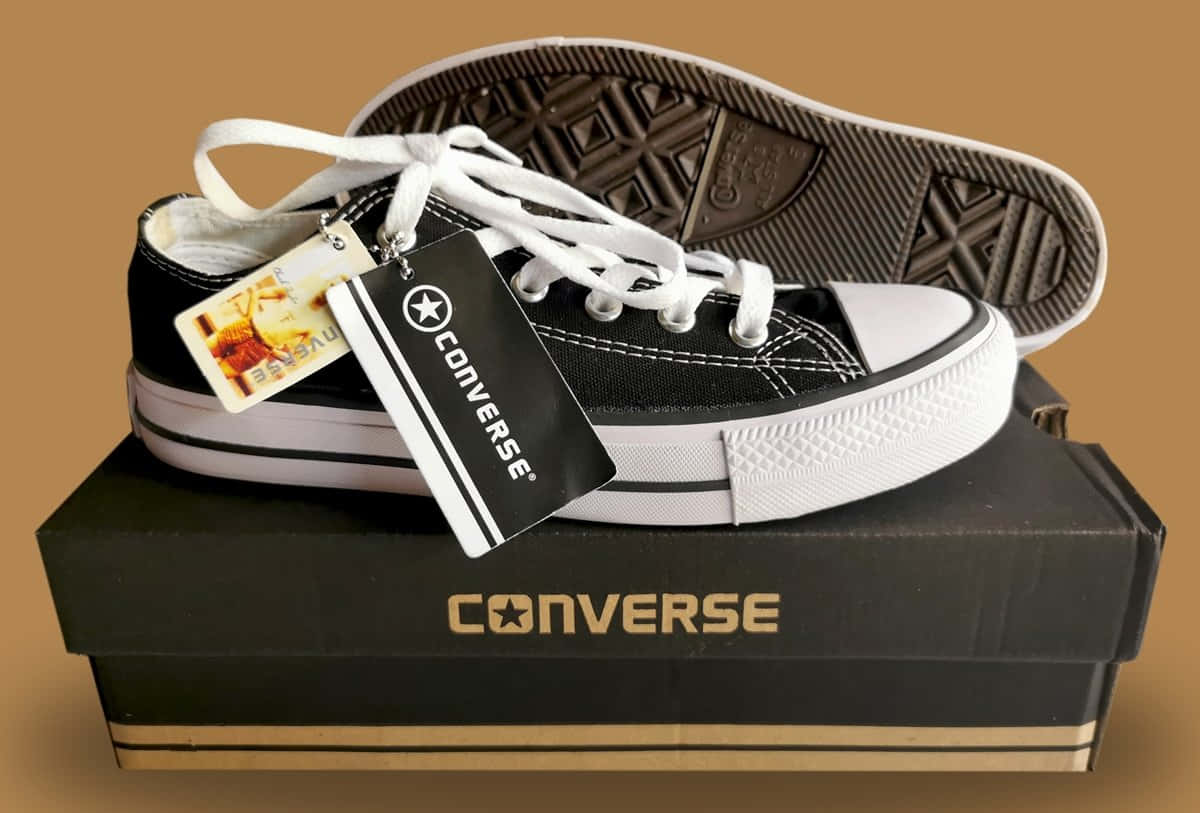 Converse 桌布 壁紙 — 一雙黑色Converse運動鞋，白色鞋帶和鞋底，放在其品牌盒子上，背景為溫暖的棕色。