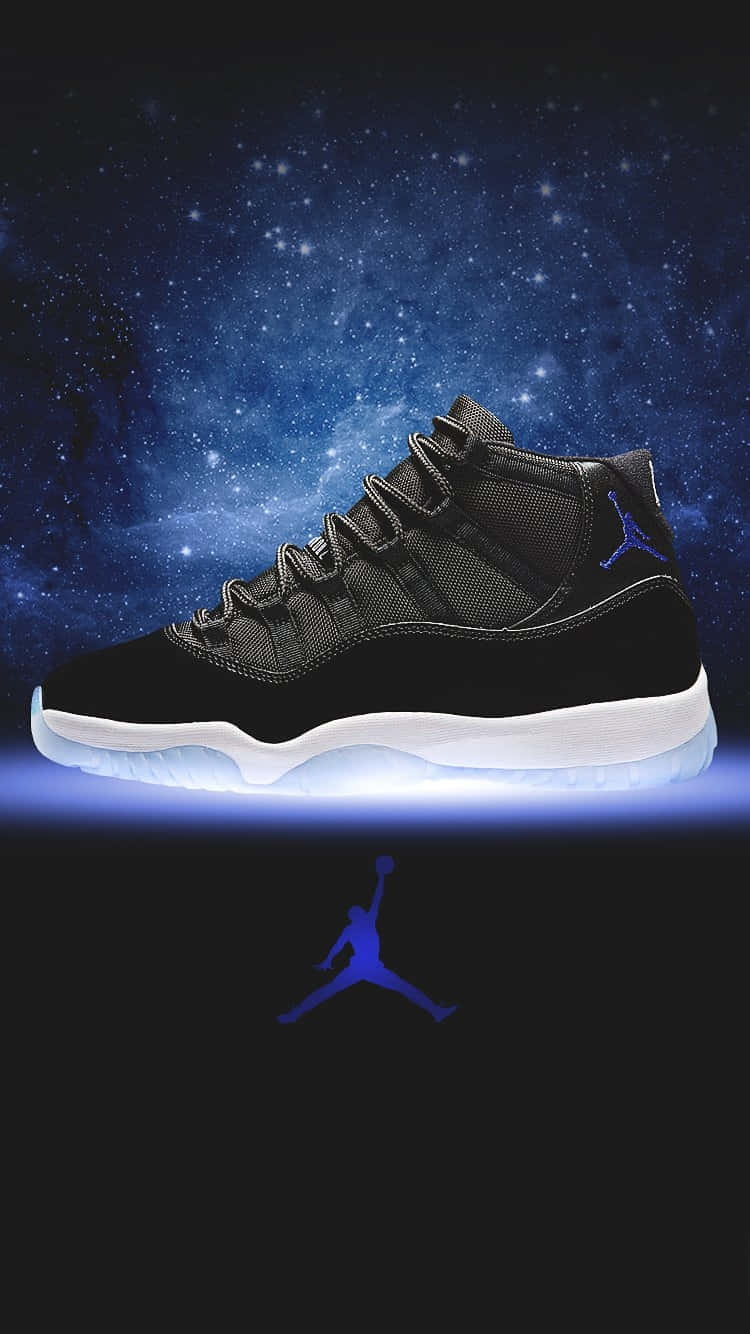 Jordan 11 桌布 壁紙 — 一雙黑色Jordan 11運動鞋在星空宇宙背景下發出藍光，下方有一個藍色Jumpman標誌。