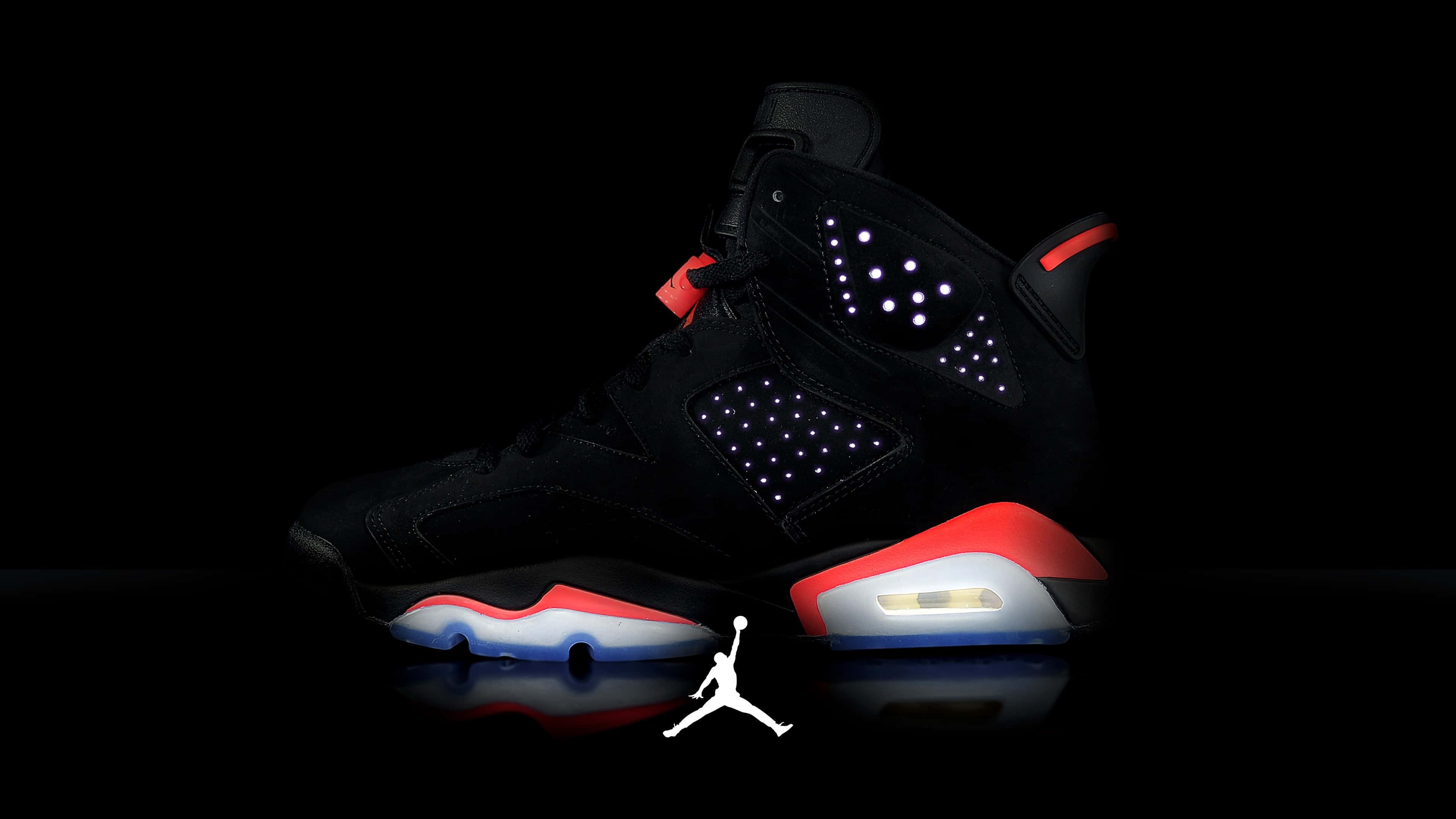 4K 桌布 壁紙 — 一雙黑色Jordan 6運動鞋，帶有發光的紅色、白色和藍色點綴，孤立地站在反射性黑色表面上，在戲劇性的工作室燈光下。