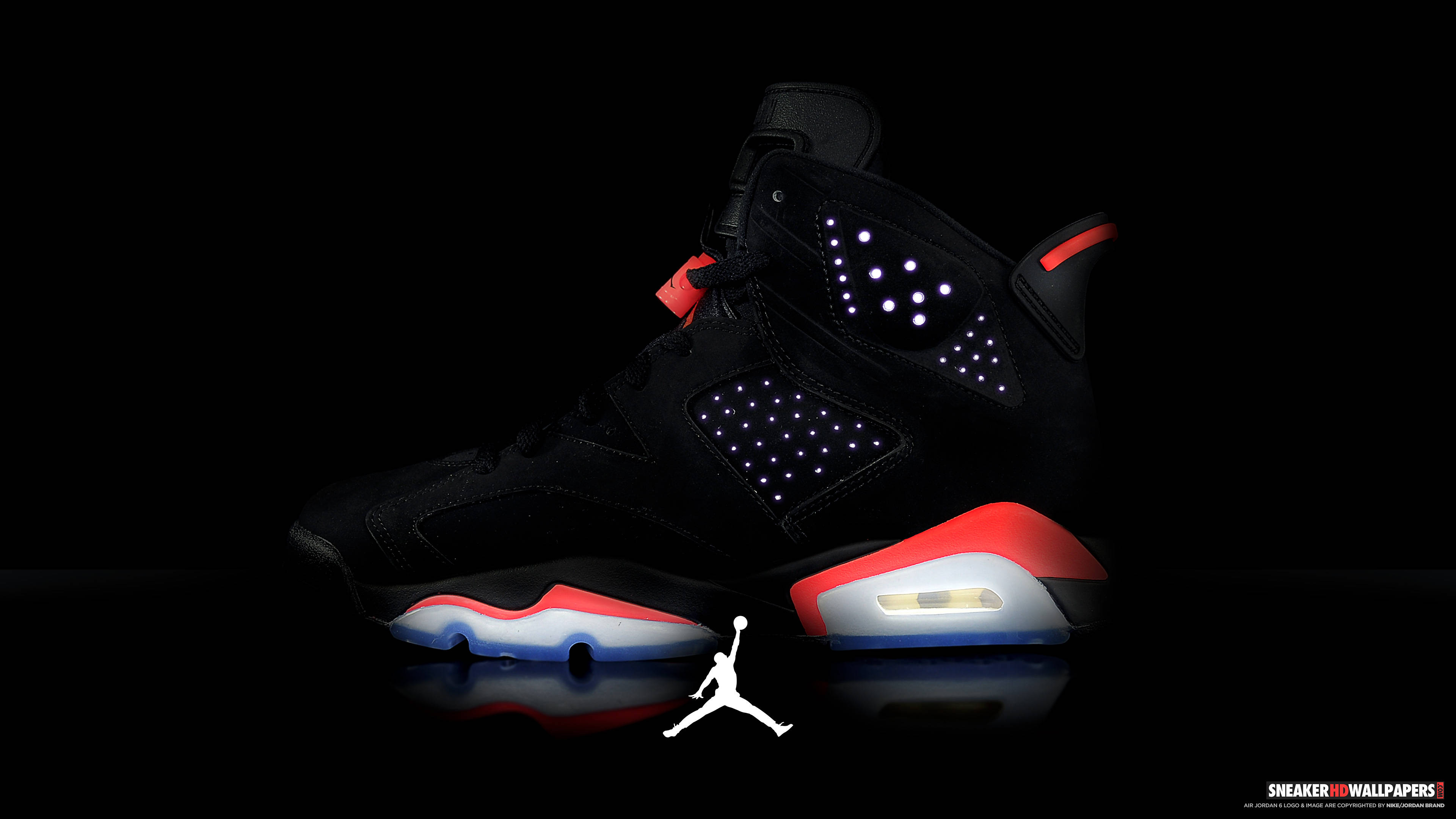 Jordan Logo 桌布 壁紙 — 一雙黑色Jordan 6運動鞋，帶有發光的紅、白、藍色點綴，孤立地站在反光的黑色表面上，下方有白色Jumpman標誌。