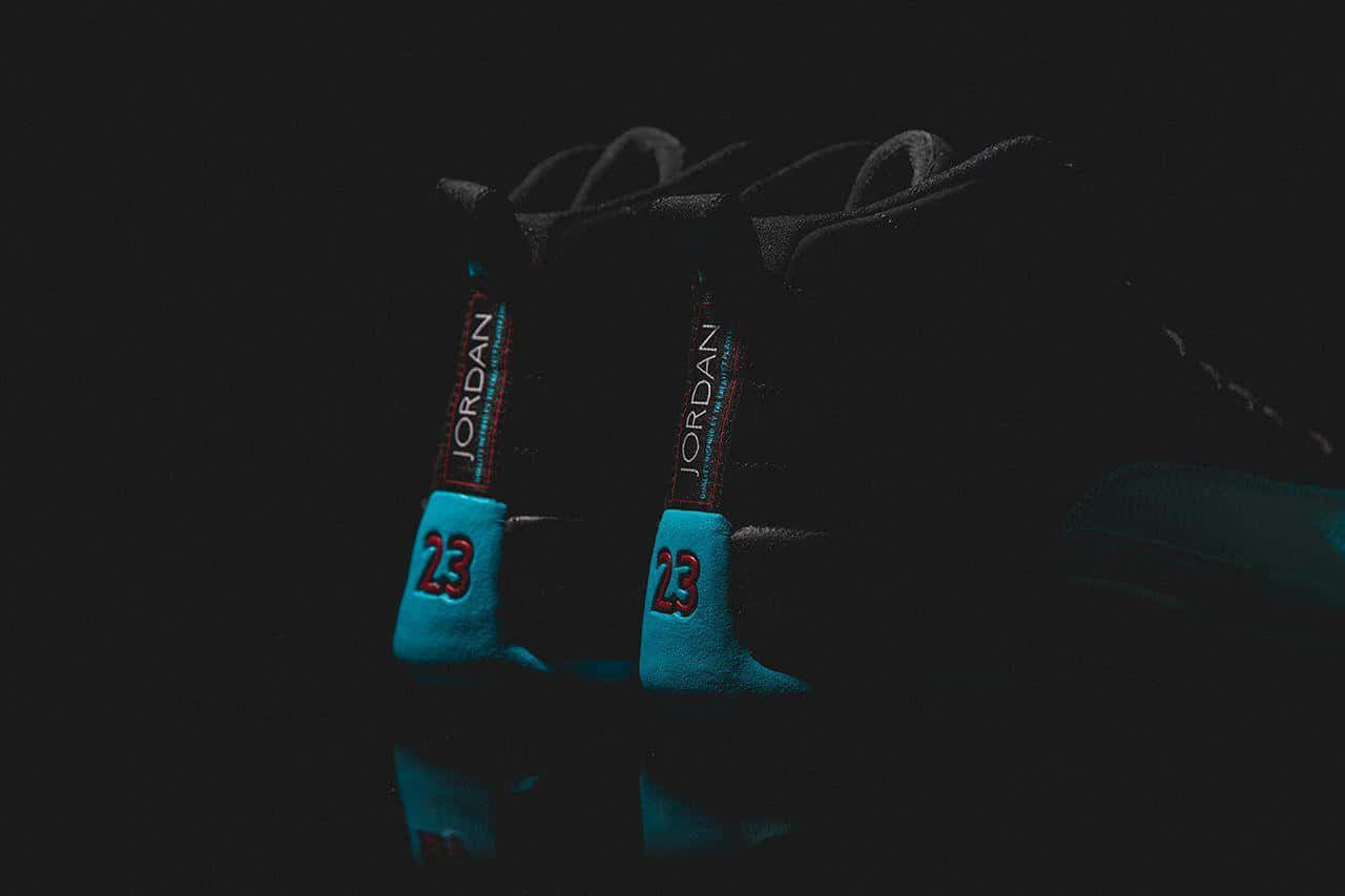Jordan球鞋 桌布 壁紙 — 一雙黑色Jordan運動鞋，帶有發光的青色和紅色點綴，在漆黑的反射表面上脫穎而出。