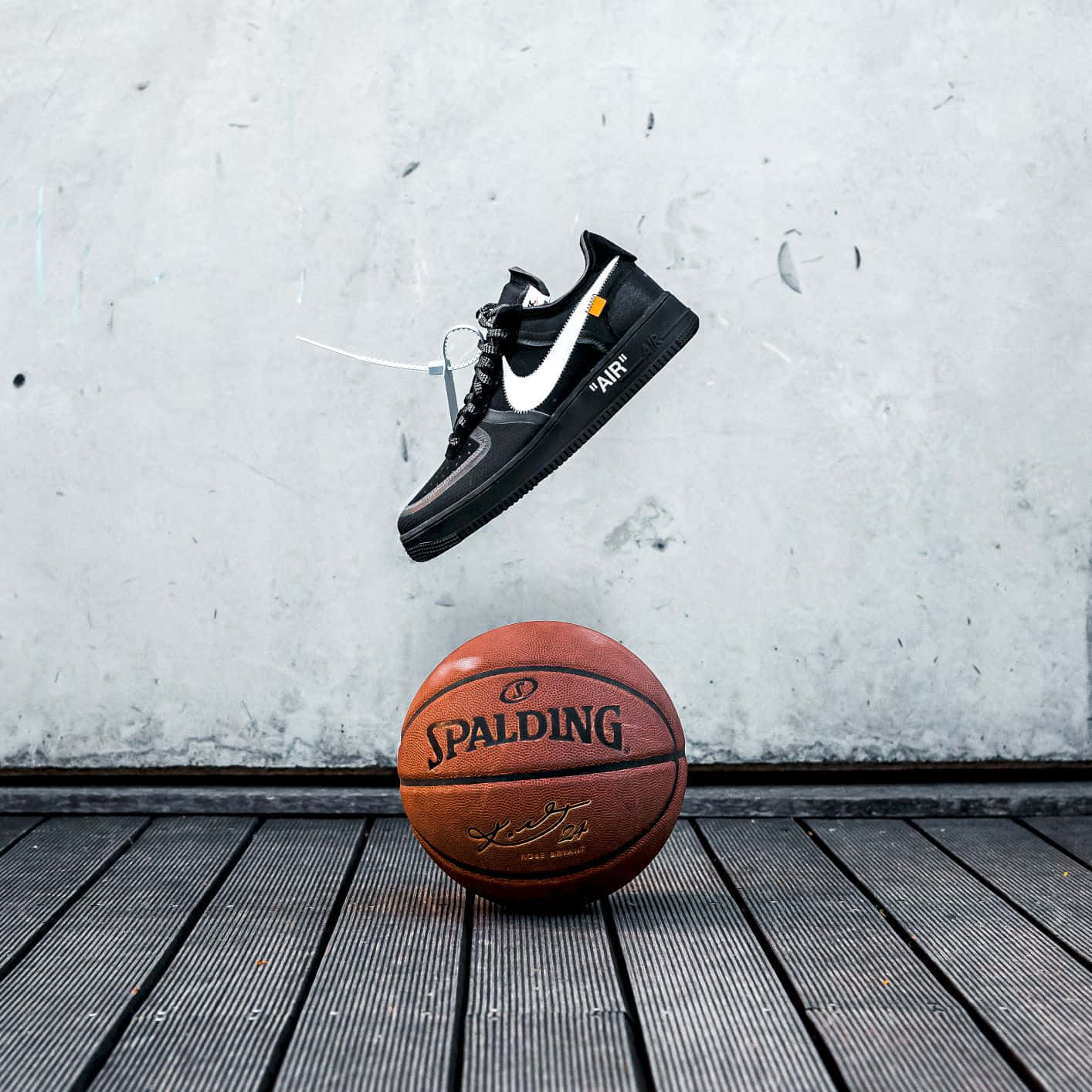Nike 節奏籃球 桌布 壁紙 — 一雙黑色Nike運動鞋懸浮在一個Spalding籃球上方，背景是磨損的木地板和混凝土牆。