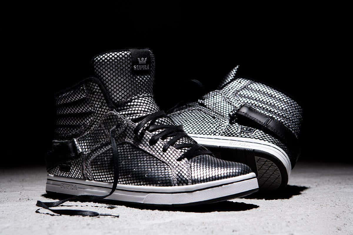 Footwear Design 桌布 壁紙 — 一雙黑色網面高筒Supra運動鞋，搭配白色鞋底和黑色鞋帶，在混凝土表面上以黑暗背景戲劇性地打光。