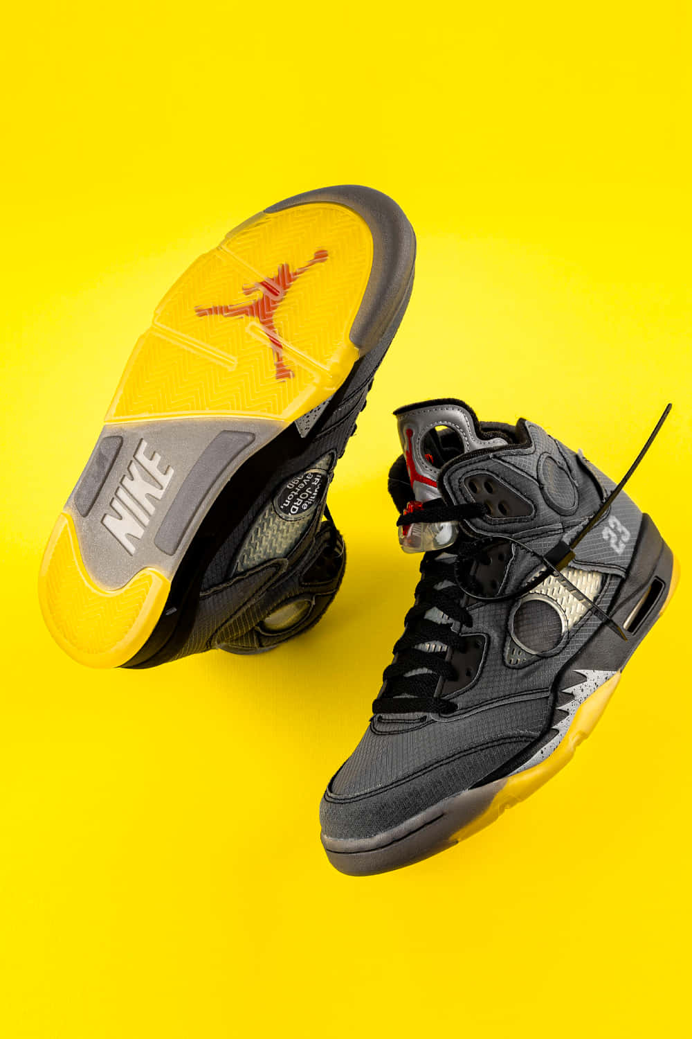 Yellow Jordan 桌布 壁紙 — 一雙黑黃色Jordan 5運動鞋，鞋底帶有紅色Jumpman標誌，背景為鮮豔的黃色。