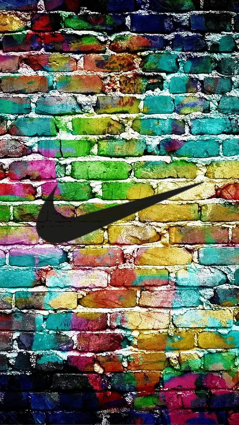 Nike 桌布 壁紙 — 一面充滿活力的塗鴉磚牆，中央有一個大膽的黑色Nike勾號標誌，背景是彩虹般的潑漆。