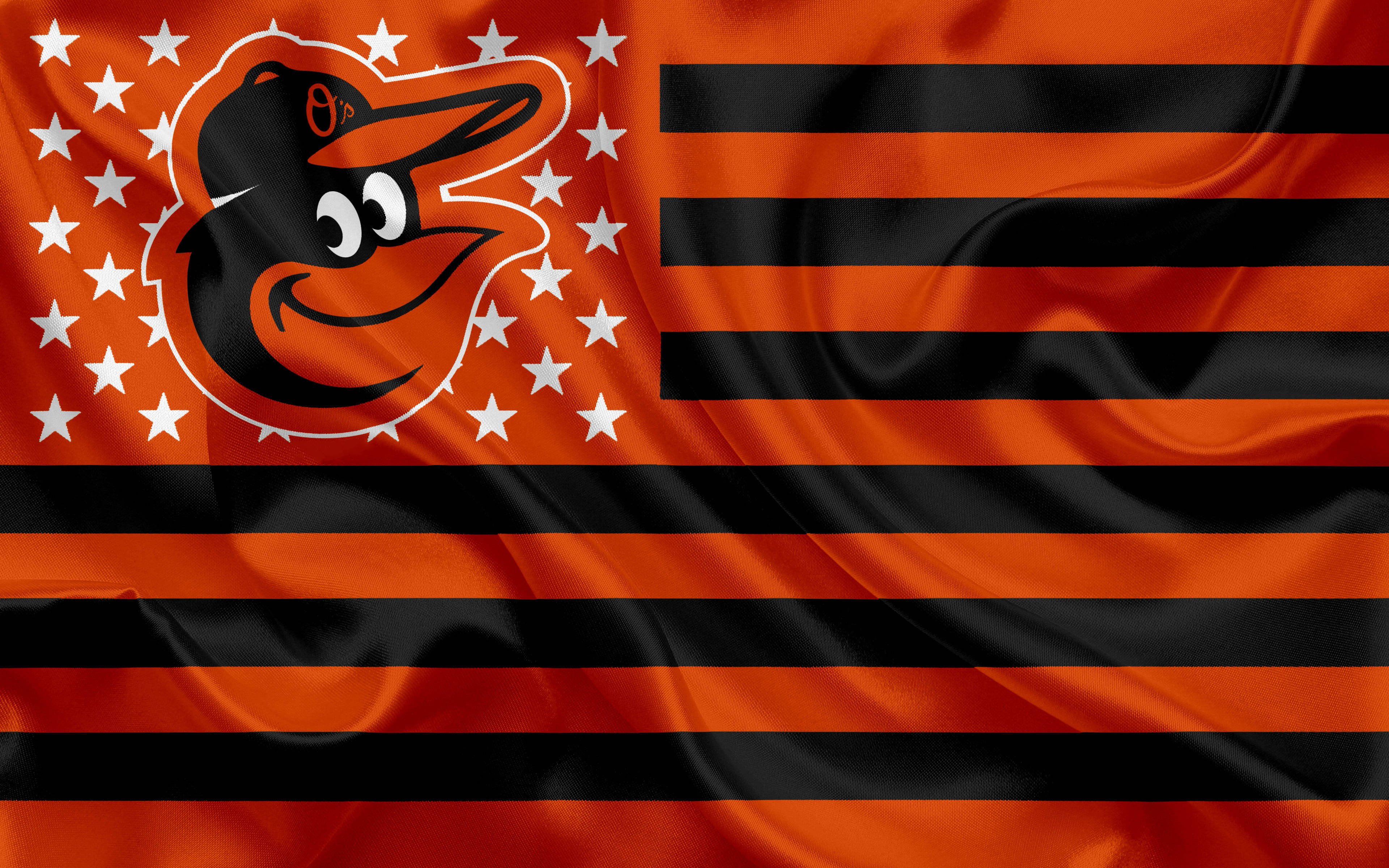 Orioles 桌布 壁紙 — 一面充滿活力的橙色和黑色旗幟，帶有卡通黃鸝吉祥物和白色星星，在風中飄揚。
