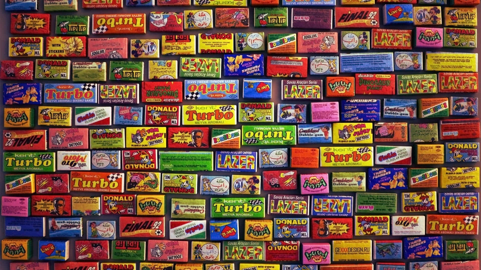 90s Computer 桌布 壁紙 — 一面充滿活力的牆，上面覆蓋著色彩繽紛的復古賽車遊戲卡帶，帶有粗體文字和卡通人物。