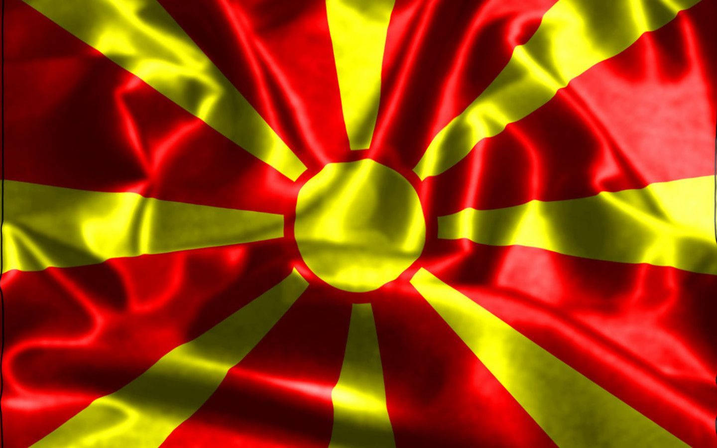 Macedonia 桌布 壁紙 — 一面充滿活力的紅金色北馬其頓國旗動態飄揚，豐富的布料褶皺捕捉光線。