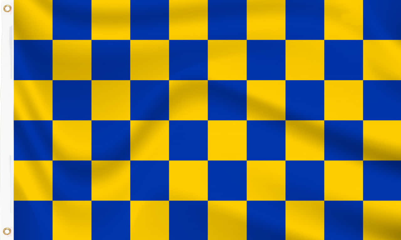 Chequered Flag 桌布 壁紙 — 一面充滿活力的藍黃格子旗在風中飄揚，布料褶皺捕捉光線。
