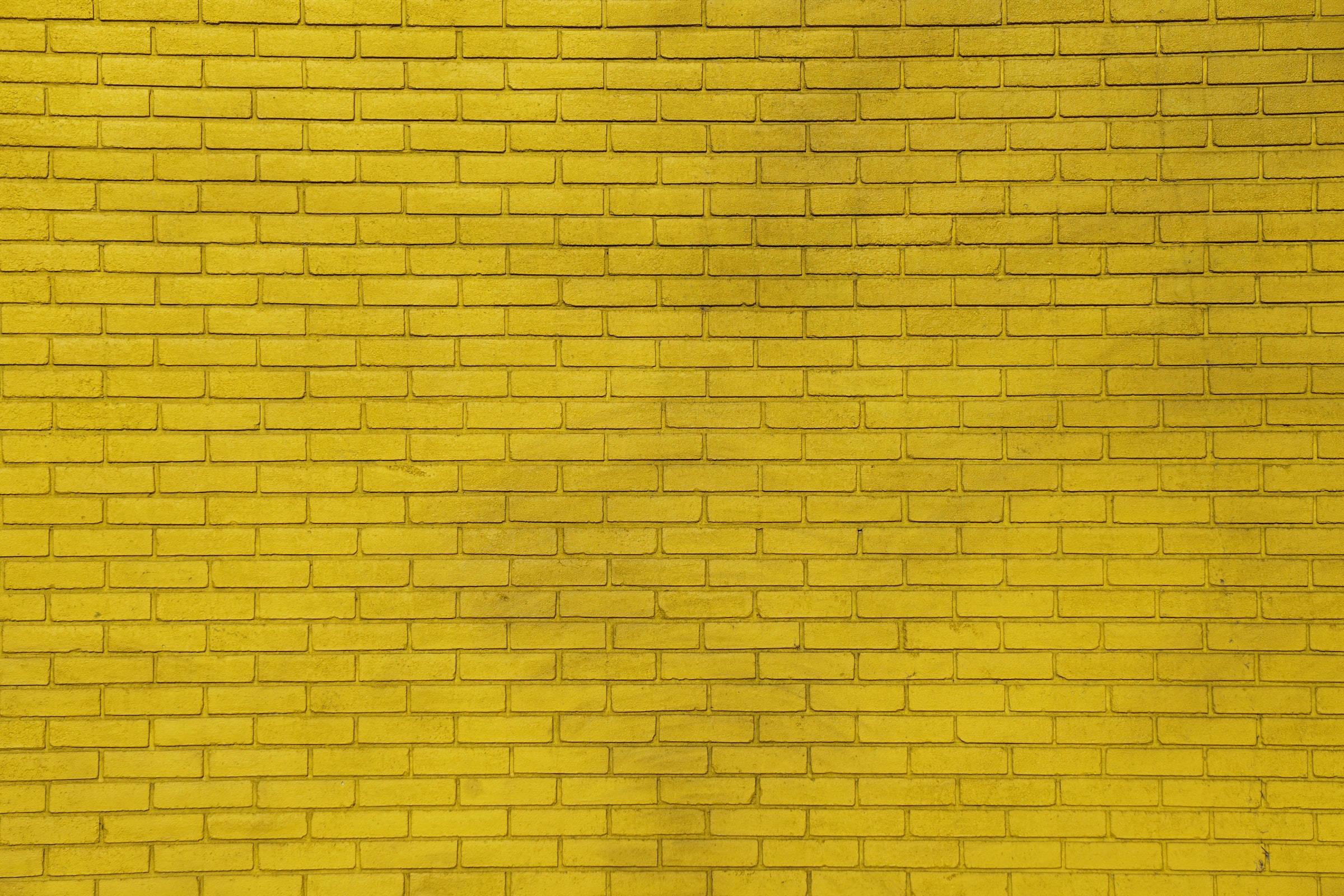 Brick Wall 桌布 壁紙 — 一面充滿活力的黃色磚牆，帶有細膩紋理和自然光線變化。