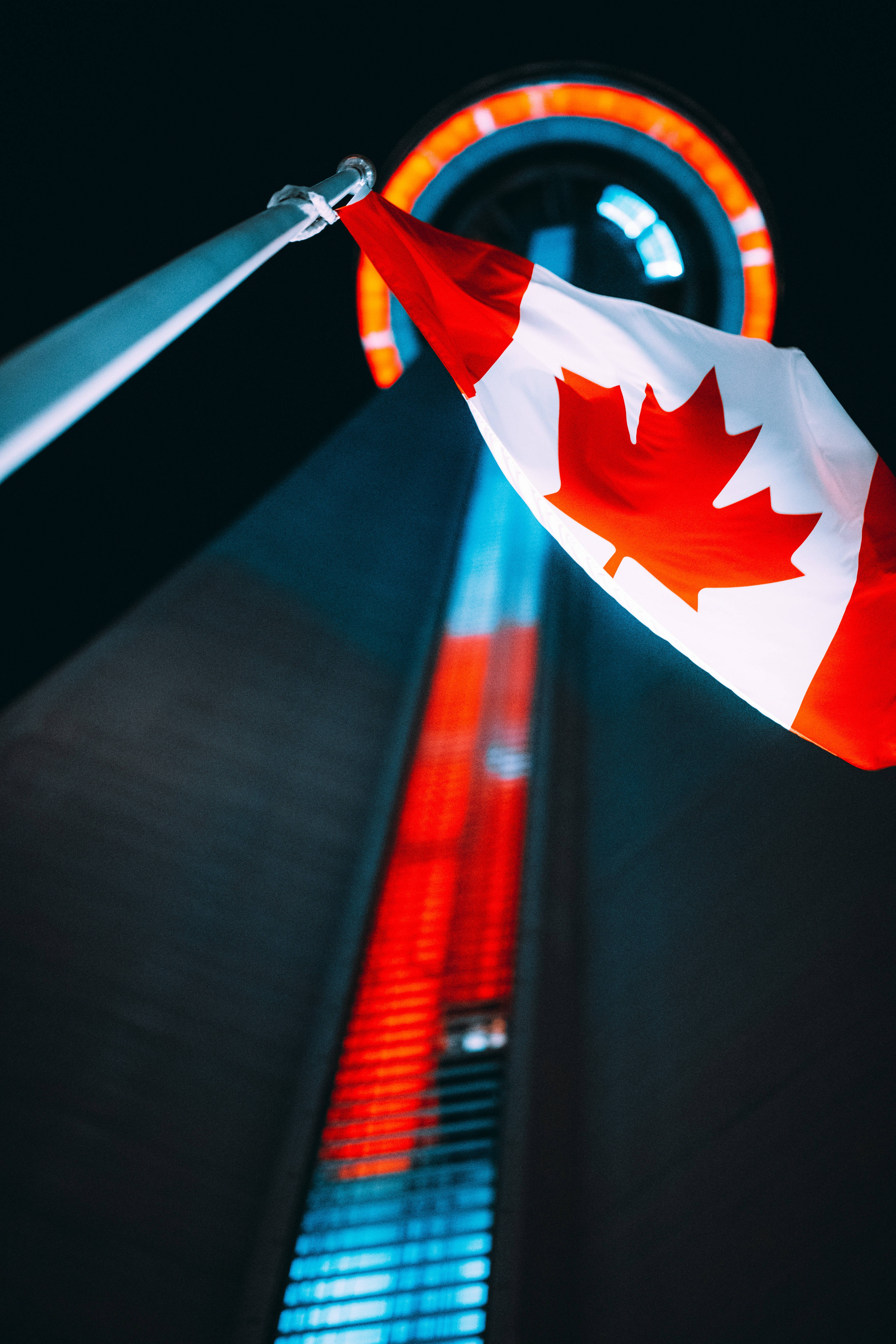 Flag 桌布 壁紙 — 一面加拿大國旗在漆黑的夜空中飄揚，旁邊是亮著燈的CN塔發光的圓形觀景台。