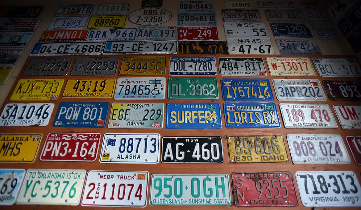 License Plate 桌布 壁紙 — 一面密集的牆壁，上面覆蓋著來自美國各州和國家的彩色復古車牌，排列成混亂的拼貼畫。