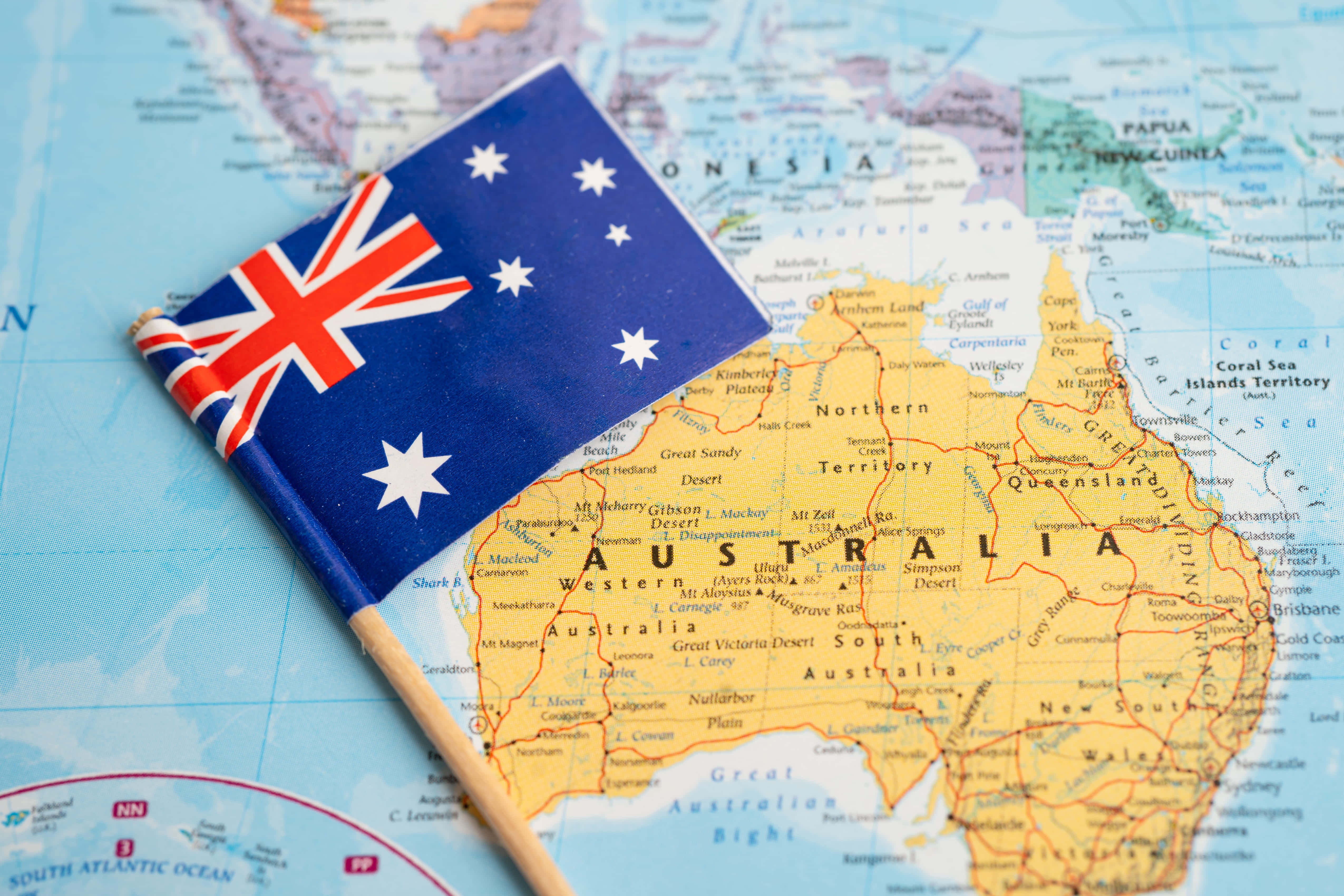 Australia 桌布 壁紙 — 一面小型澳洲國旗放在一張詳細地圖上，突顯該國的地理環境及周邊海域。